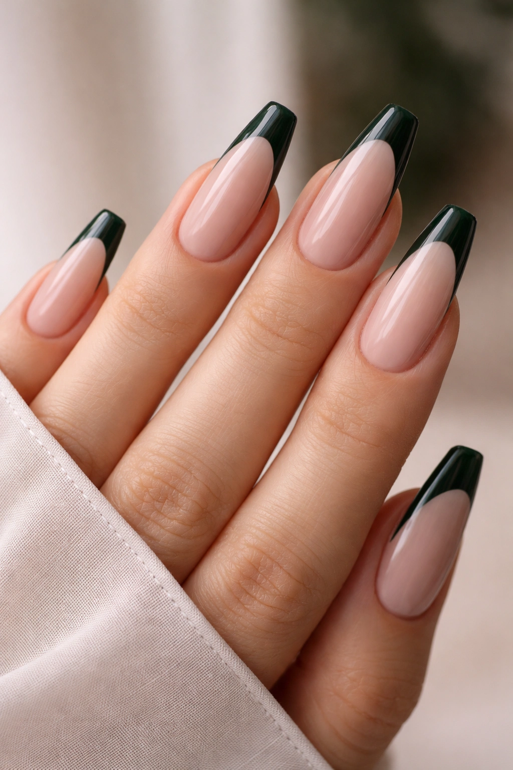 Close-up of nude ballerina nails with dark green French tips.