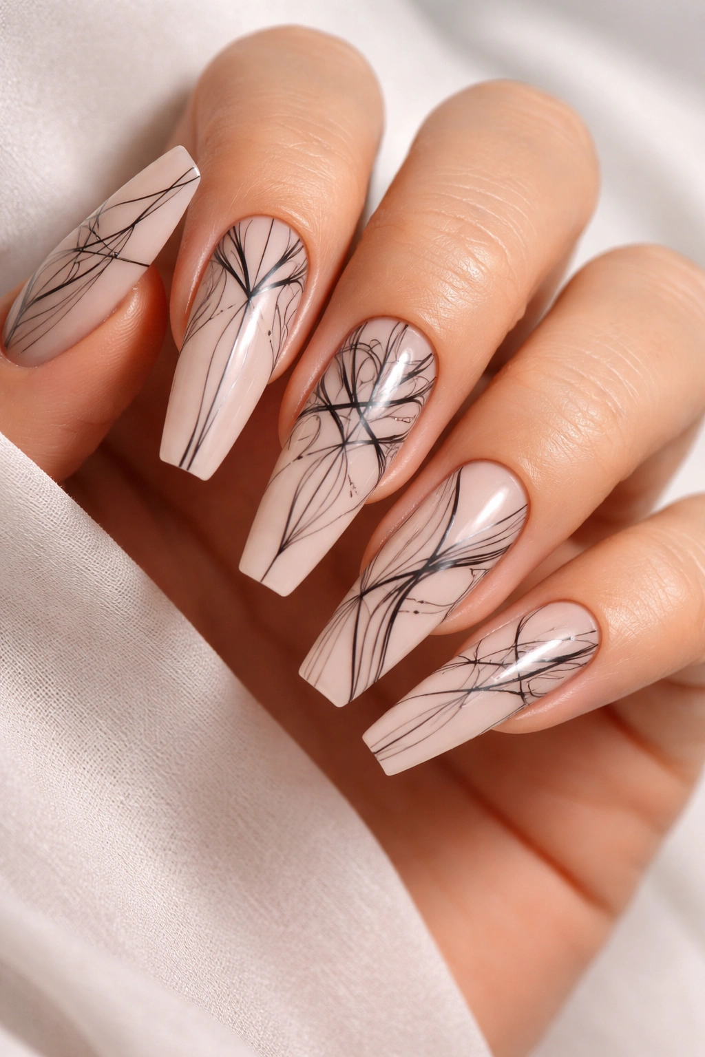 Nude coffin nails with black line art on a neutral background