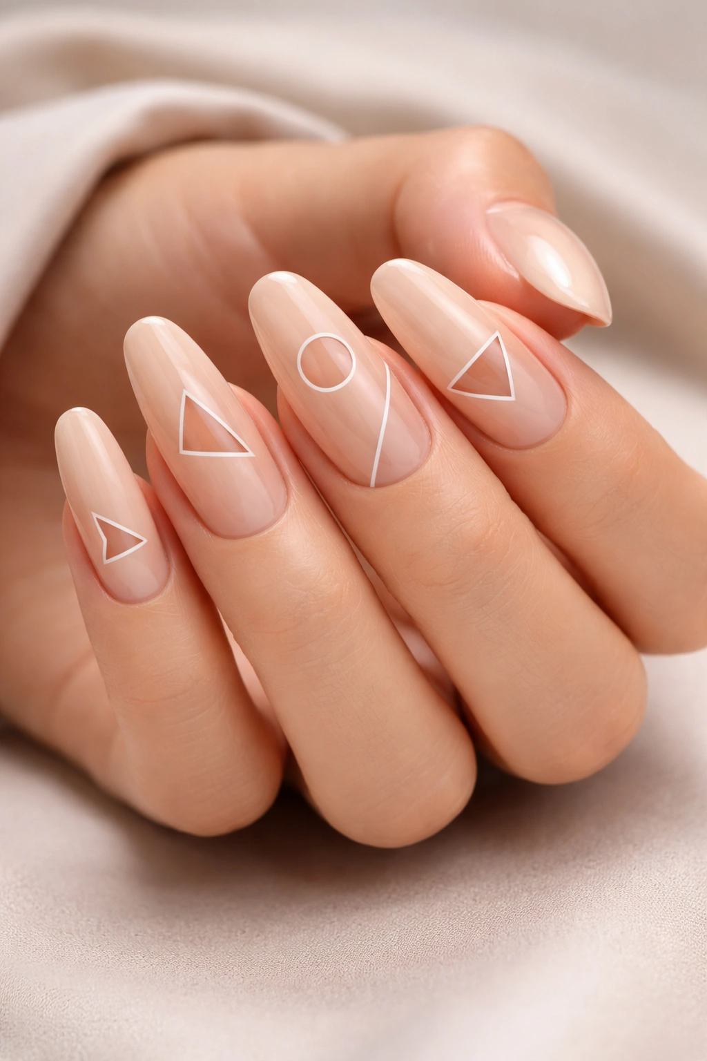 Close-up of nude long round acrylic nails featuring geometric negative-space shapes on a neutral background