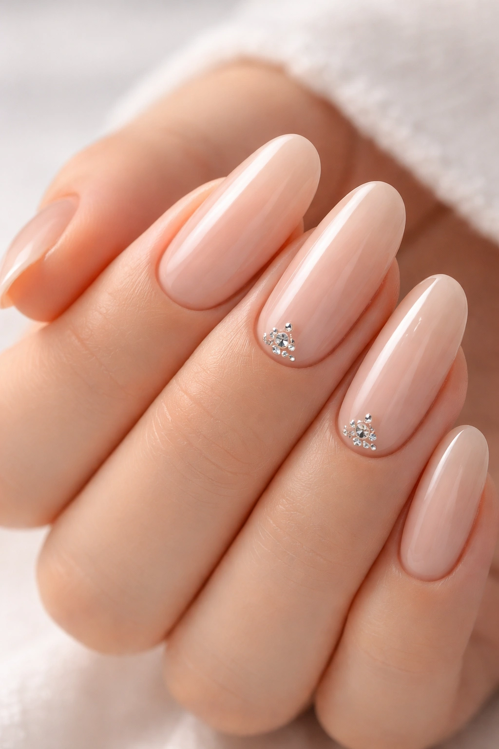 Close-up of nude nails with clear rhinestones on one or two nails