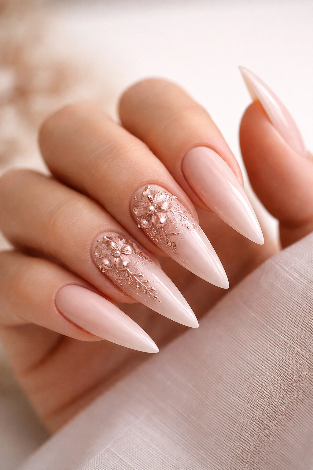 Close-up nude nails with rose gold floral details on stiletto nails