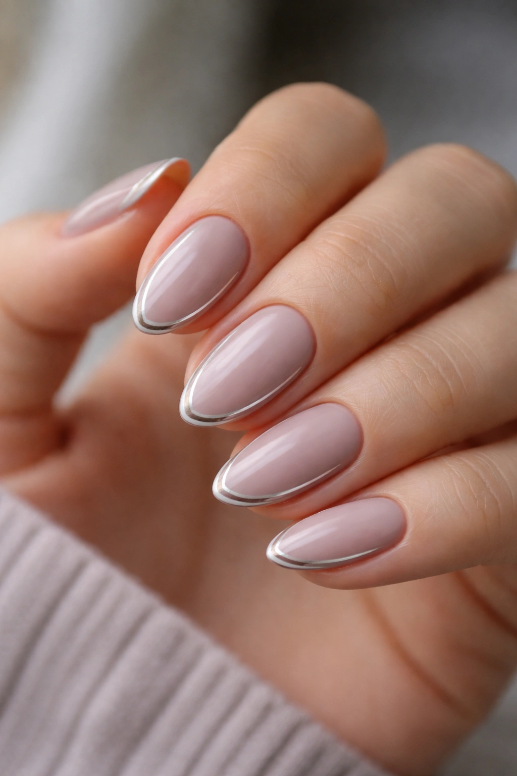 Close-up of cool-tone nude almond nails with a thin silver liner