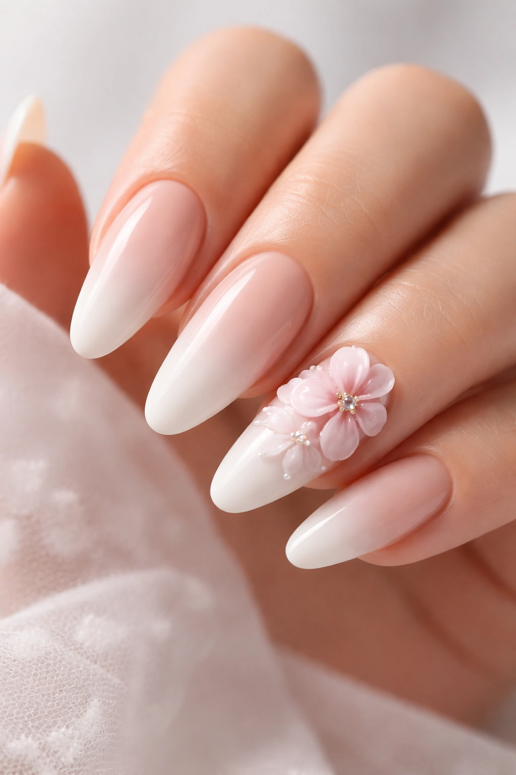 Close-up of nude-to-white ombre manicure with 3D pink flowers on accent nails