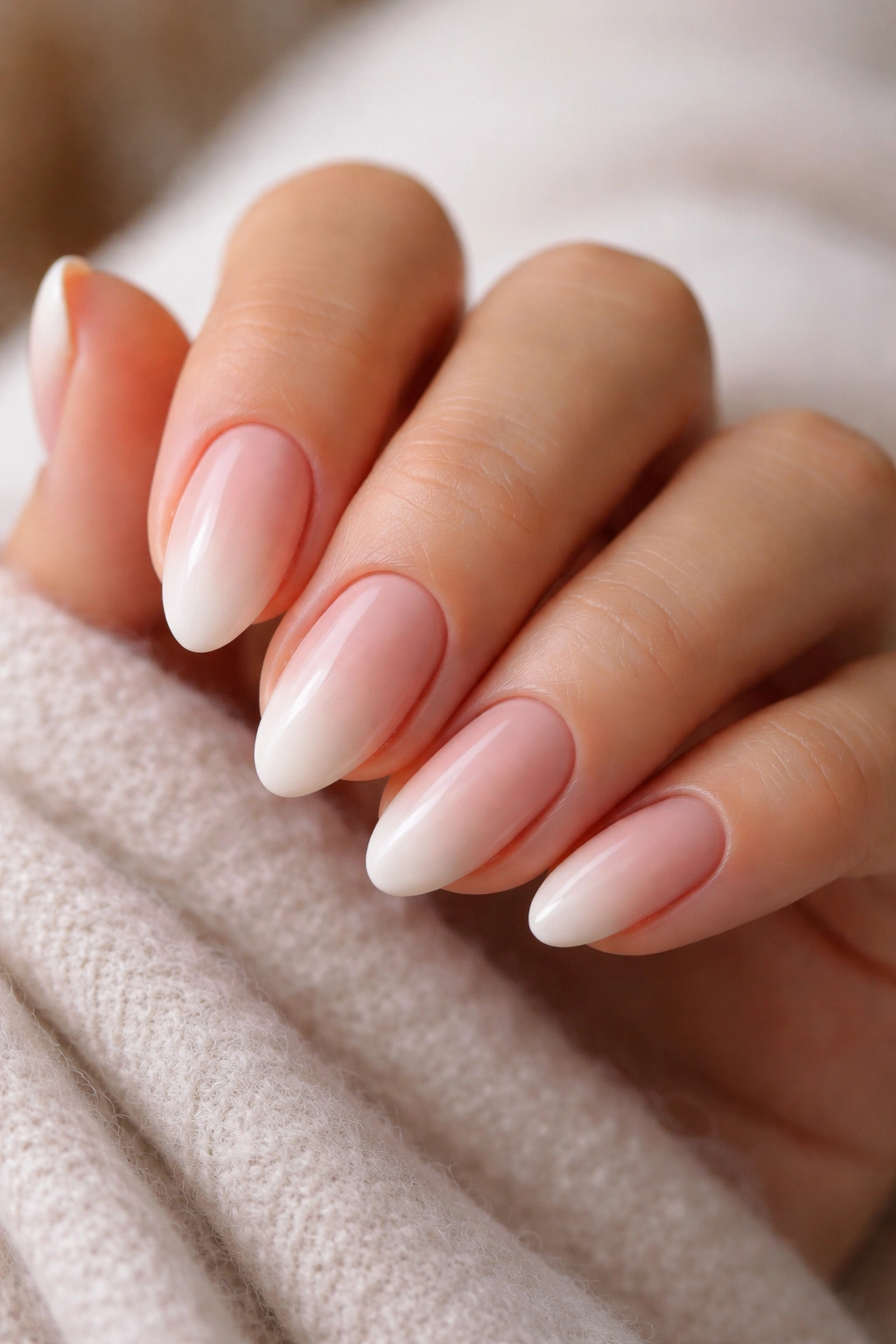 Close-up of nude ombre short almond nails with soft gradient