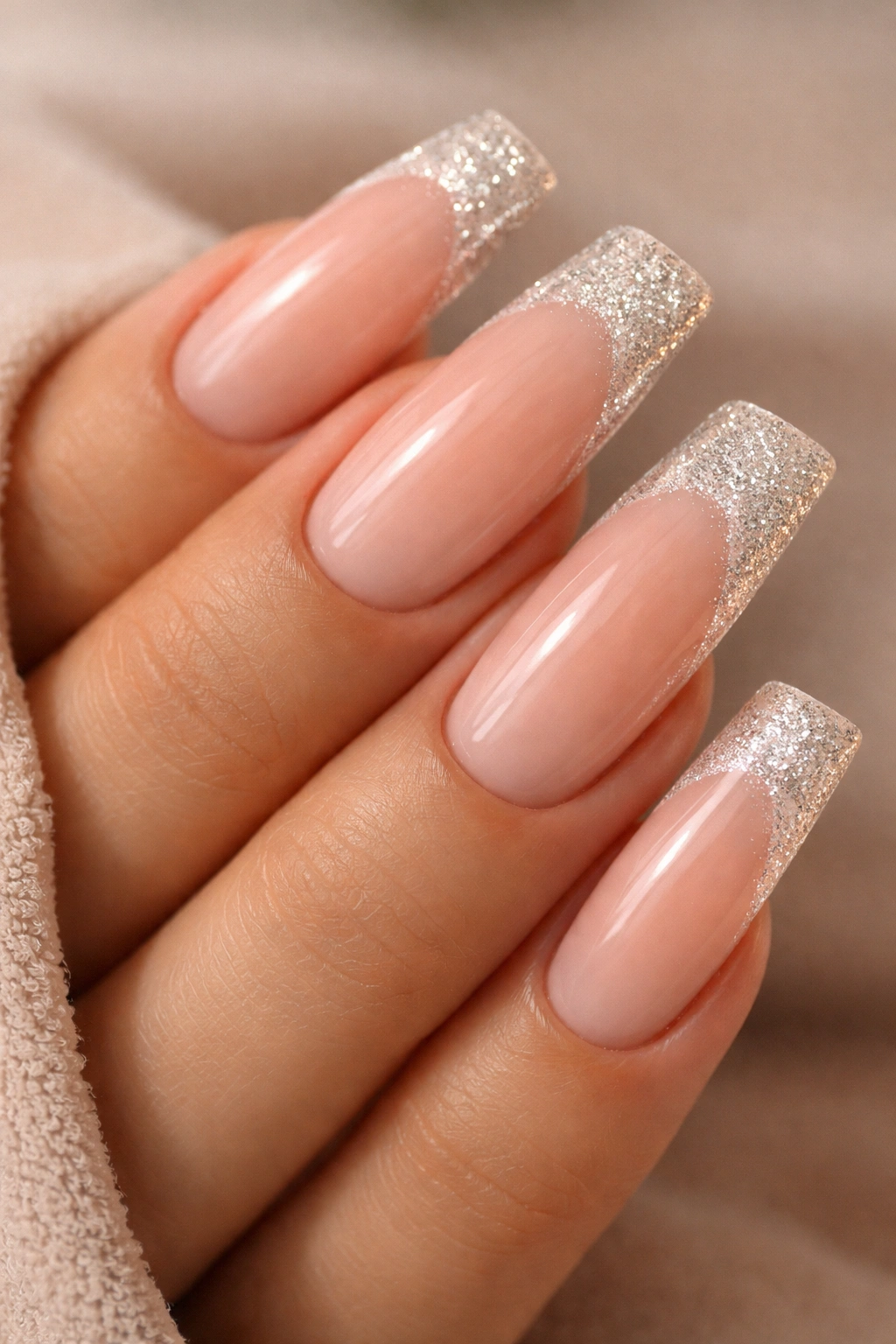 Nude ombre nails with glittery French tips on long duck nails.