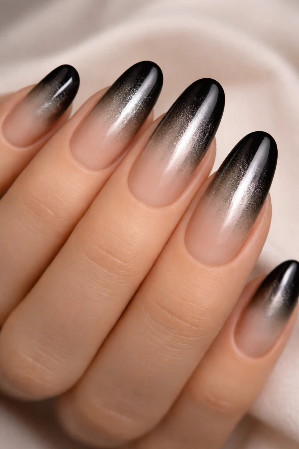 Close-up of nude-to-black metallic ombre long round nails