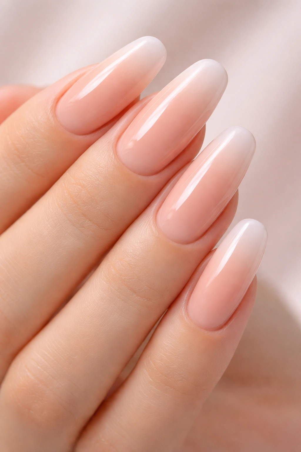 Close-up of nude ombre nails on long round acrylic nails with a soft gradient