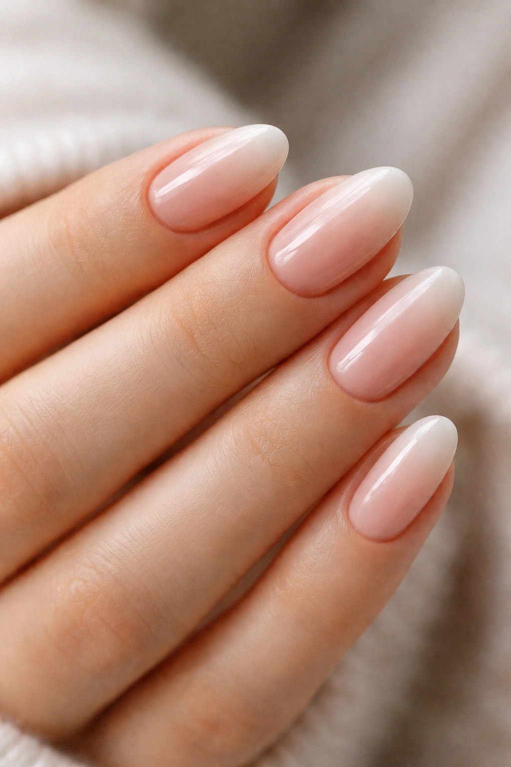 Close-up of short almond nails with nude ombré gradient.