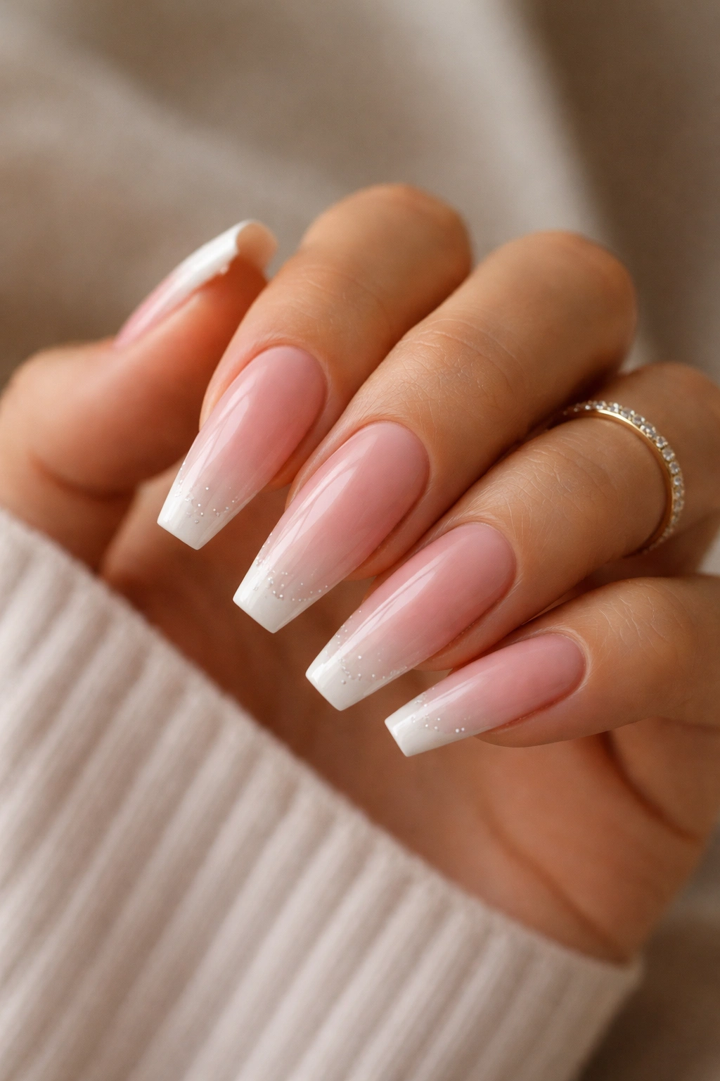 Close-up of long coffin nails with pink-to-nude ombre and white tip details