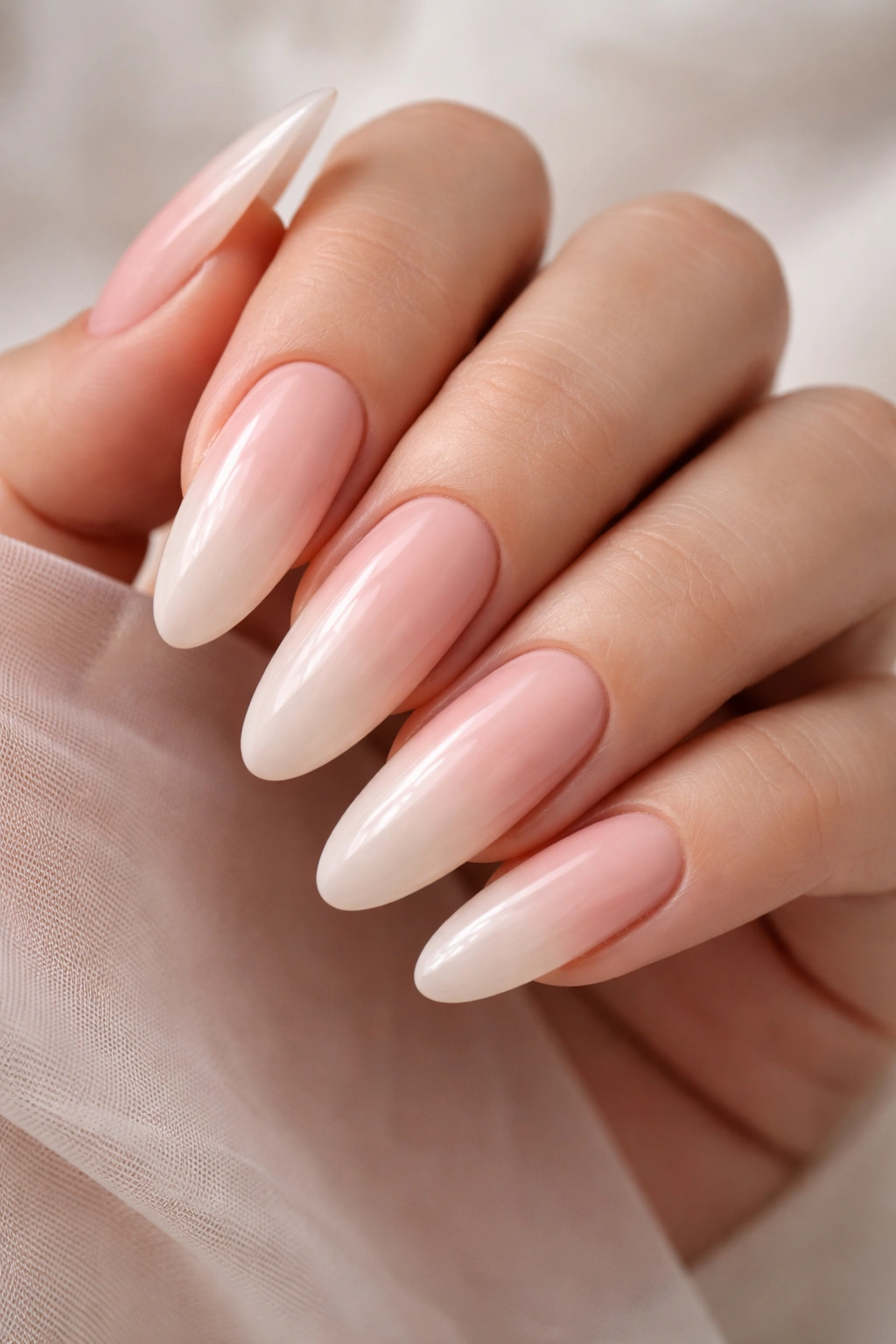 Close-up of long nude ombre oval nails with a soft pink to beige fade