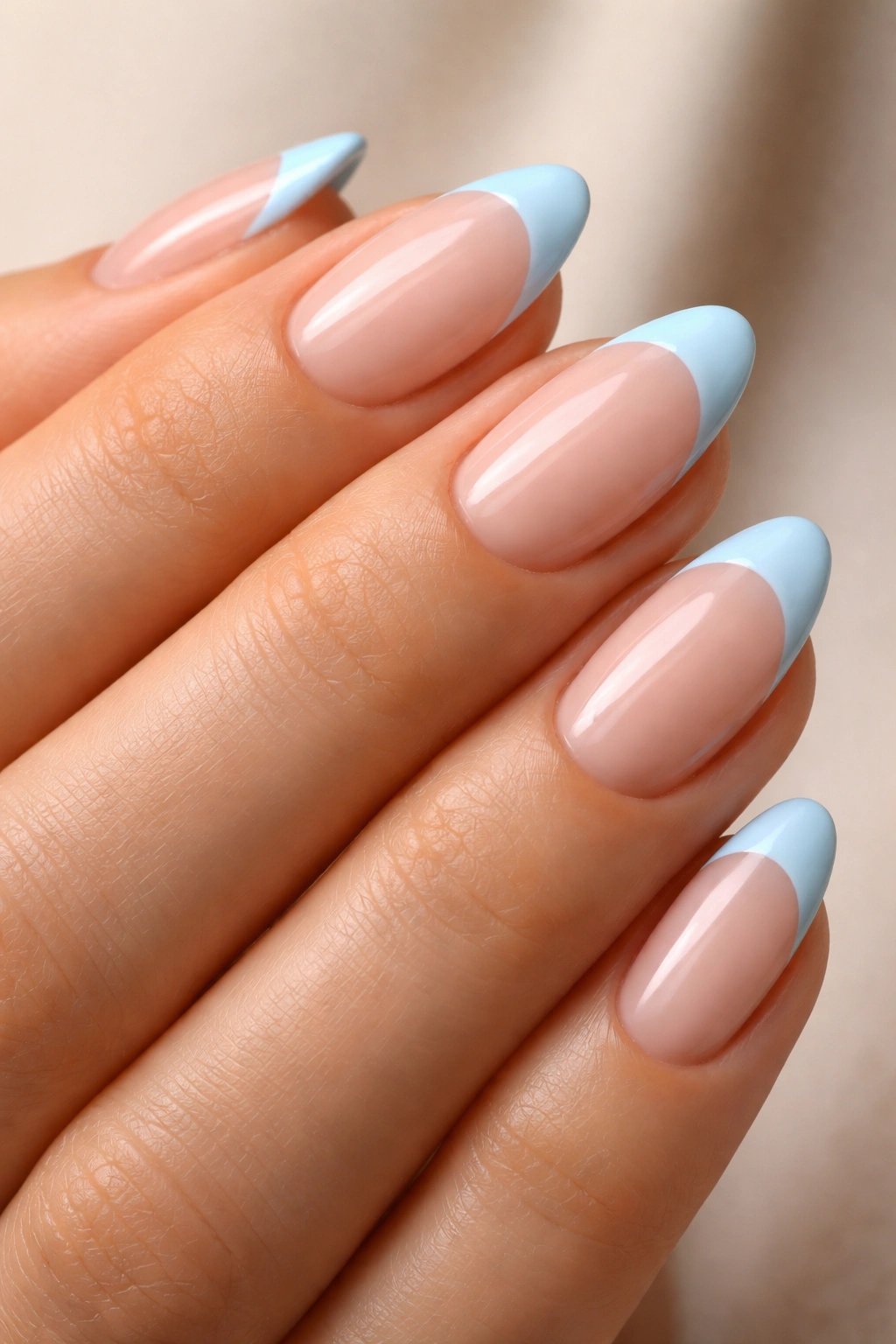 Close-up of short almond nails with nude pink base and baby blue tips