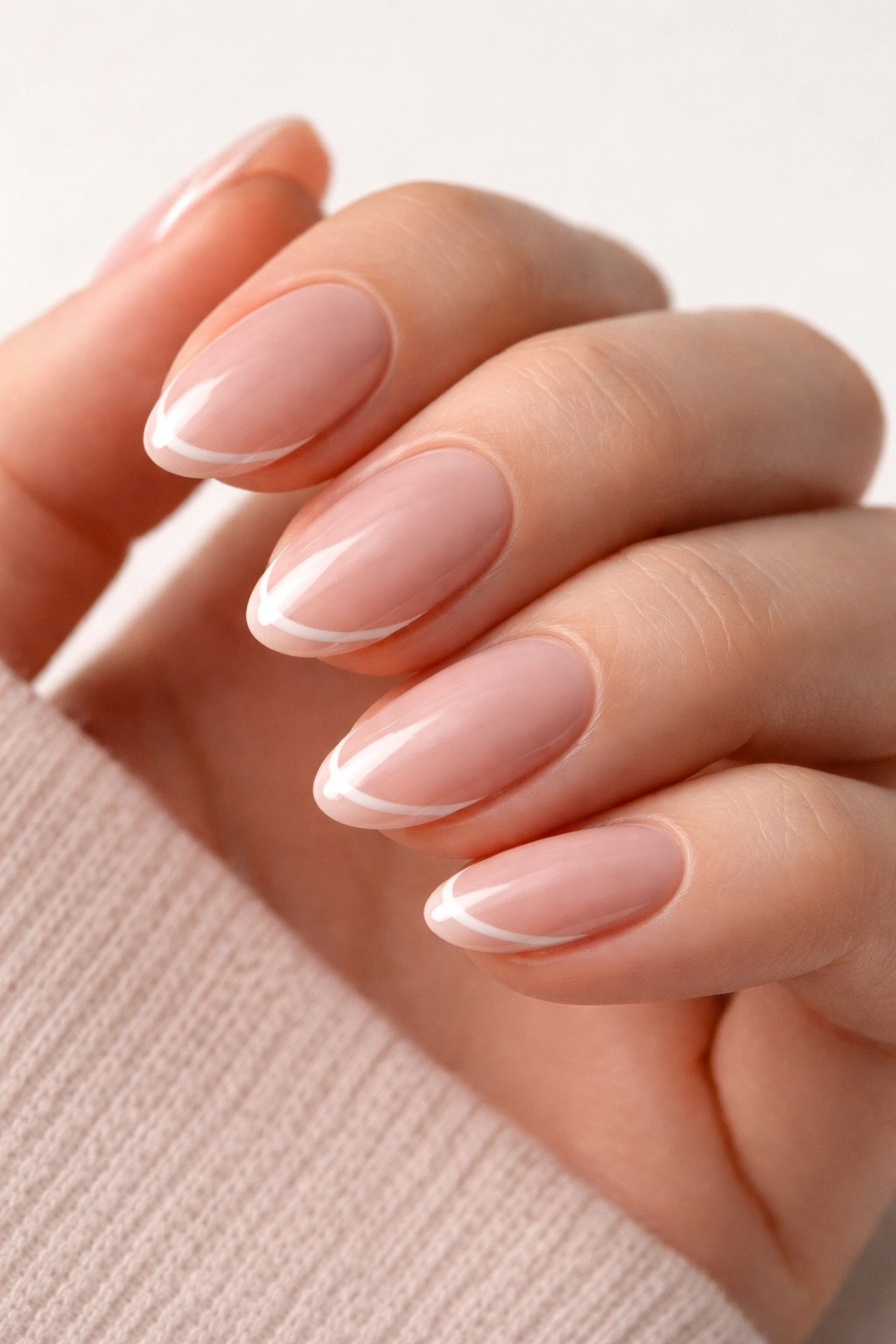 Short almond nails featuring nude pink base with a thin line near the edge