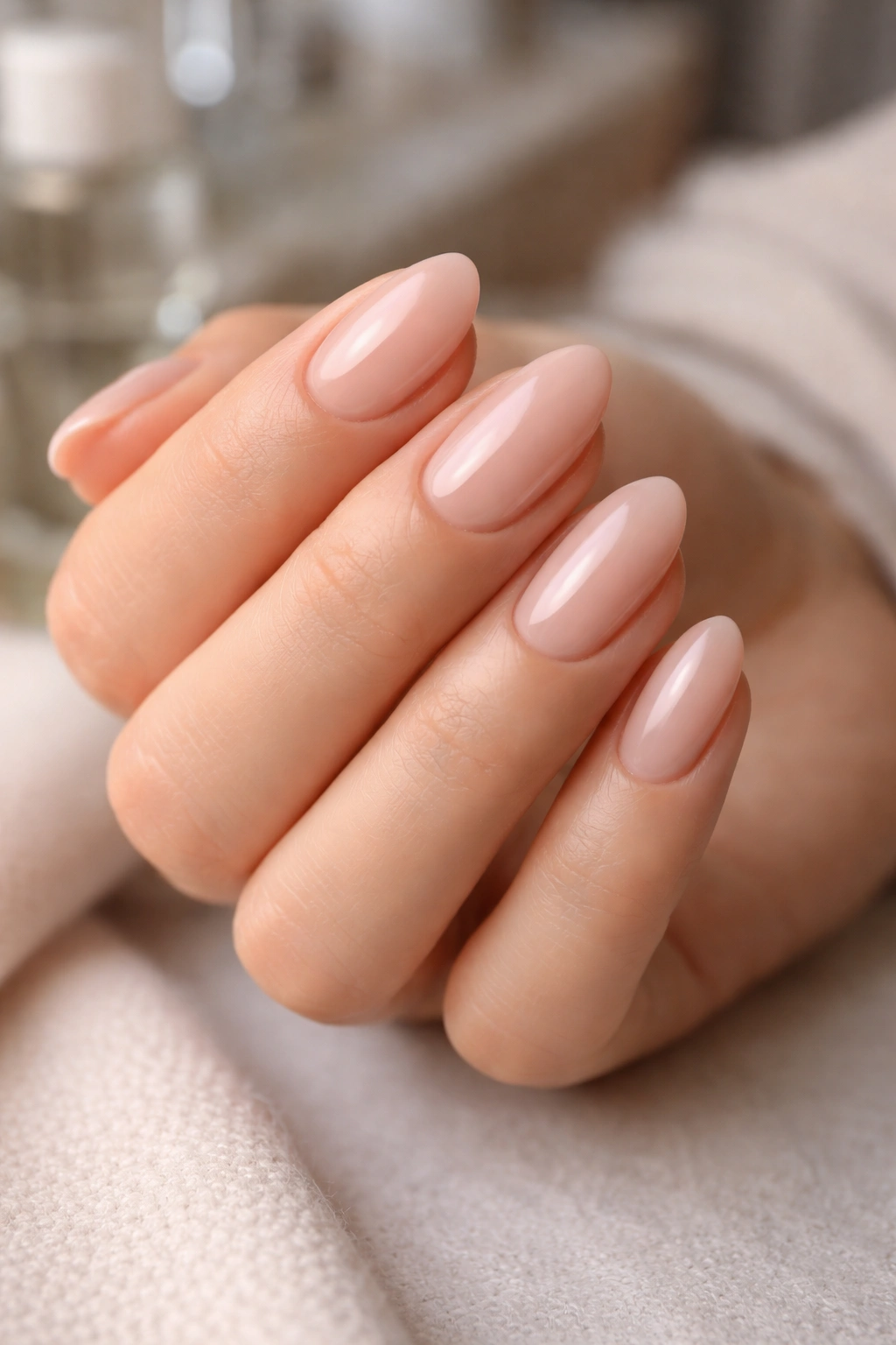 Close-up of pale nude pink almond nails with smooth finish.