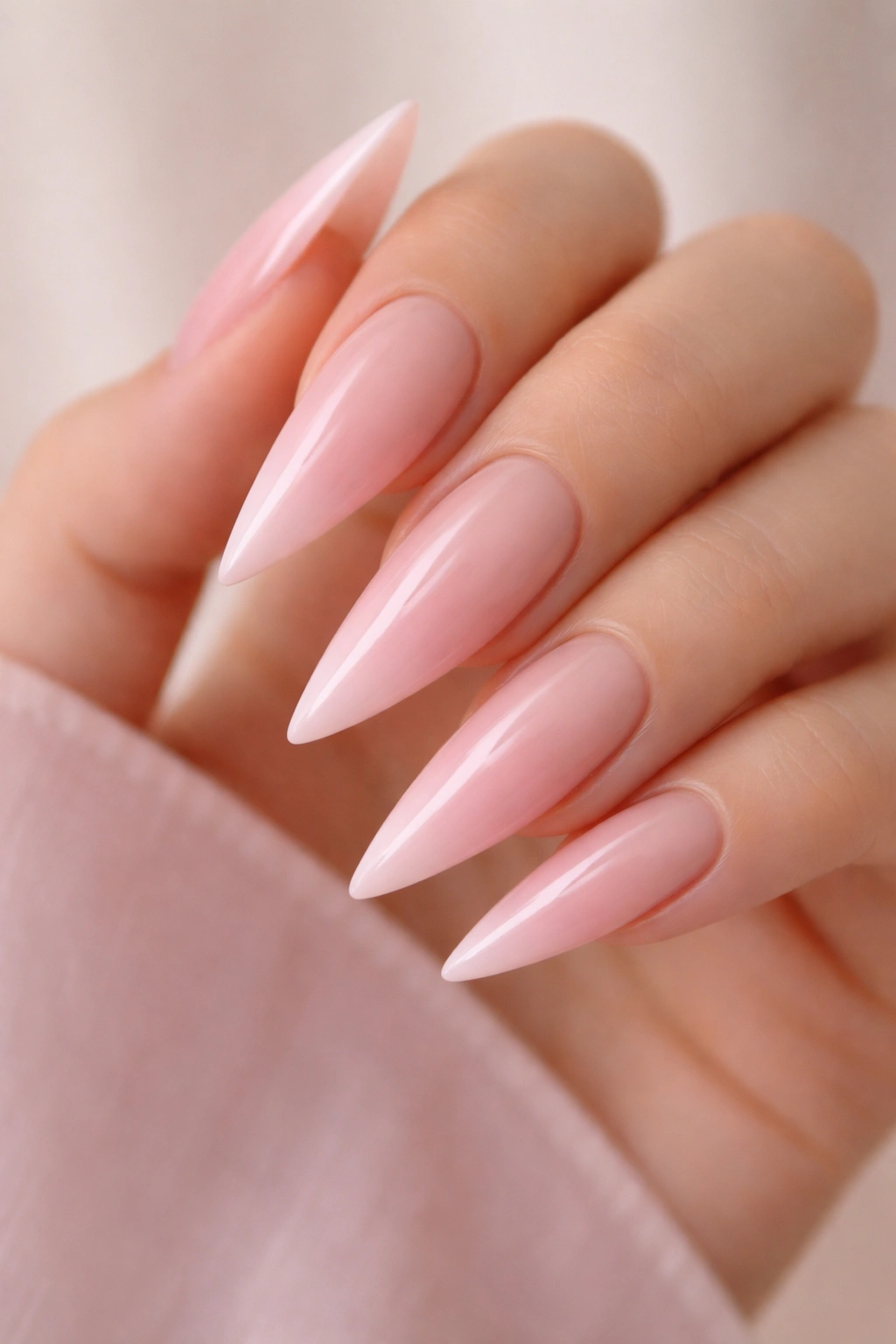 Close-up nude to pink gradient stiletto nails.
