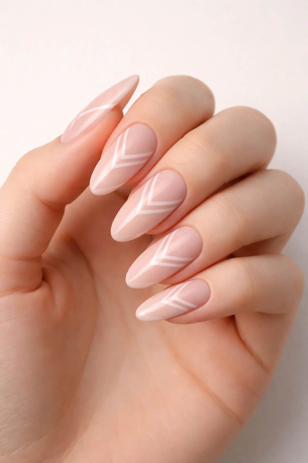 Close-up of long oval nude pink nails with negative-space geometric designs