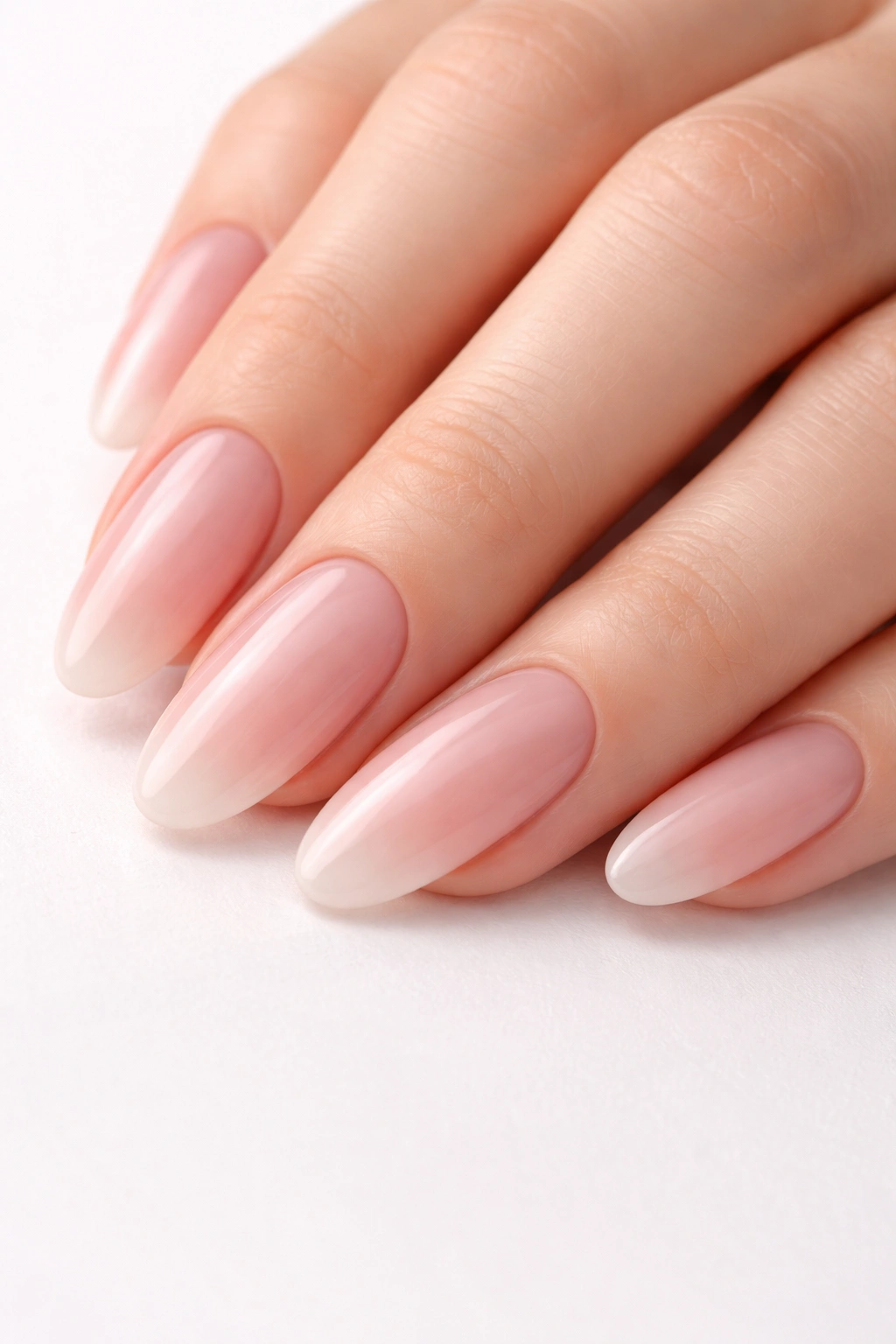 Nude pink ombre nails with sheer tips on long oval shape