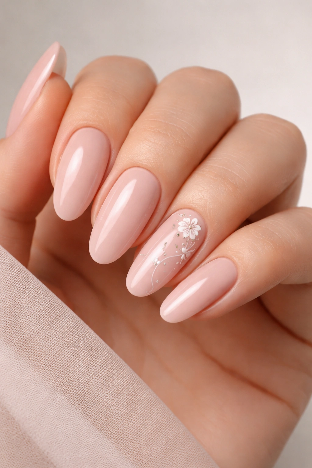 Nude pink nails with detailed ring finger art on long oval nails