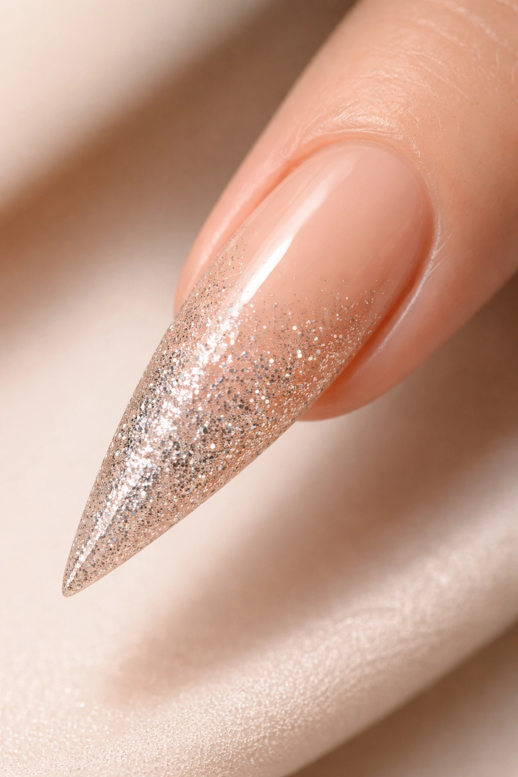 Close-up of nude stiletto nail with glitter gradient