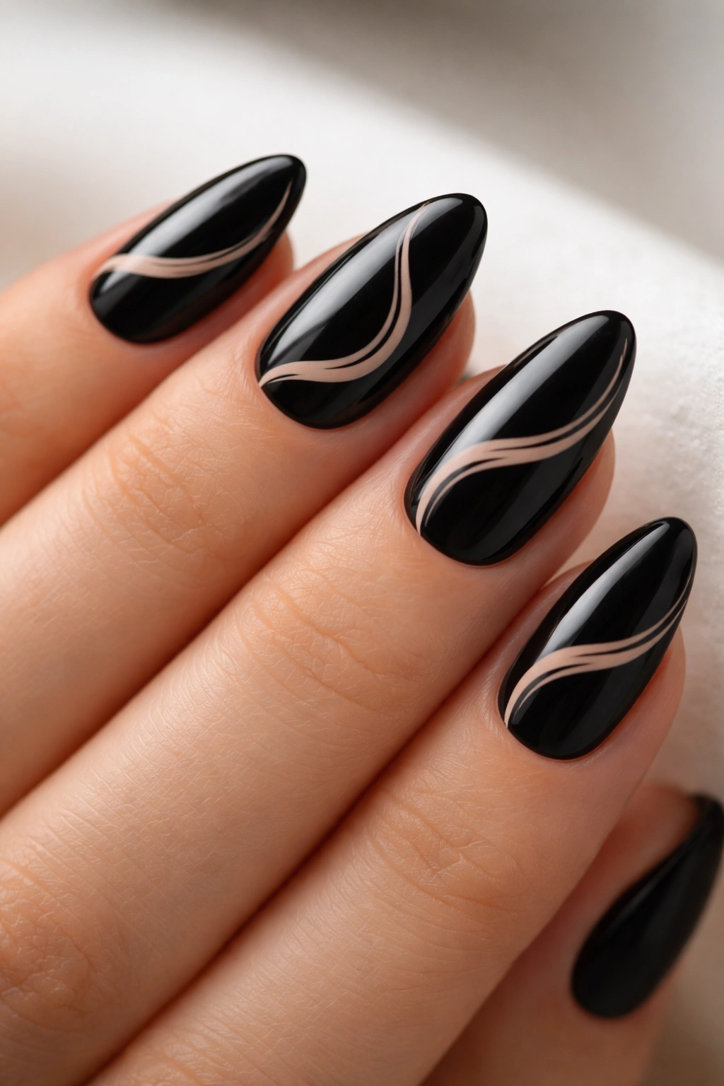 Close-up of black almond nails with subtle nude swirls