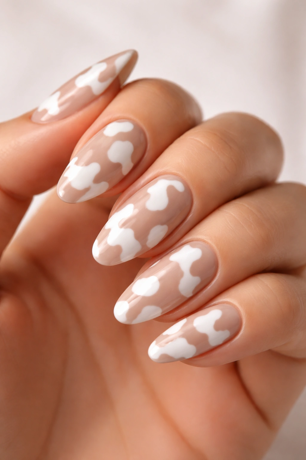 Close-up of nude and white cow print nails