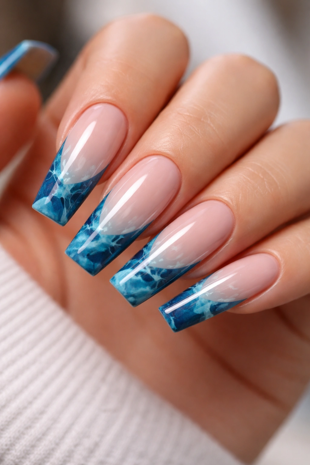 Long ballerina nails with ocean blue marble tips on a nude base