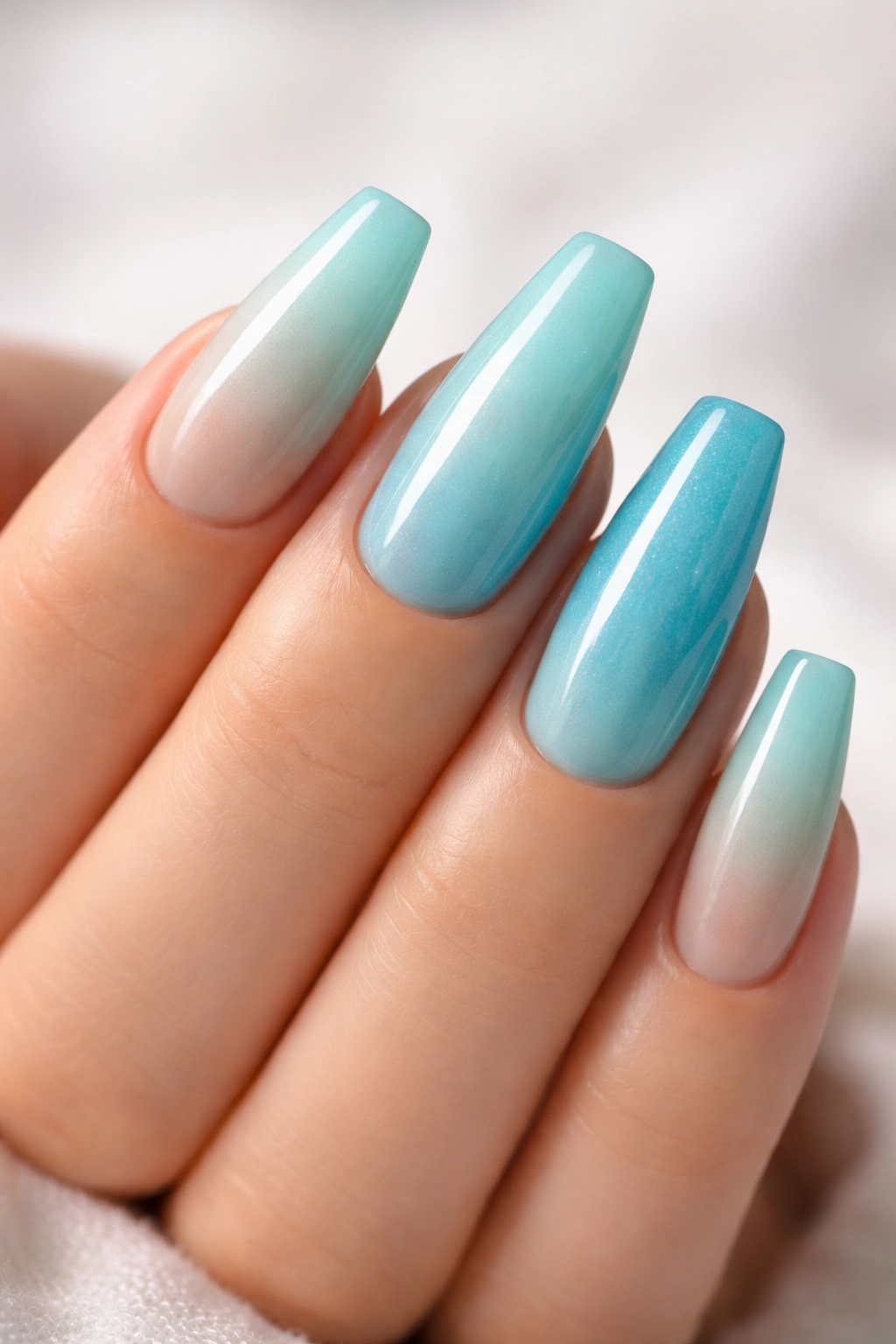 Close-up of ocean blue ombré ballerina nails with glossy finish