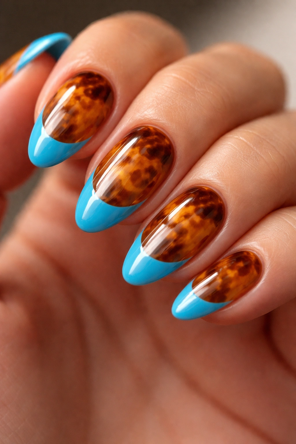 Close-up of a short almond nail with ocean blue tip over tortoiseshell base.