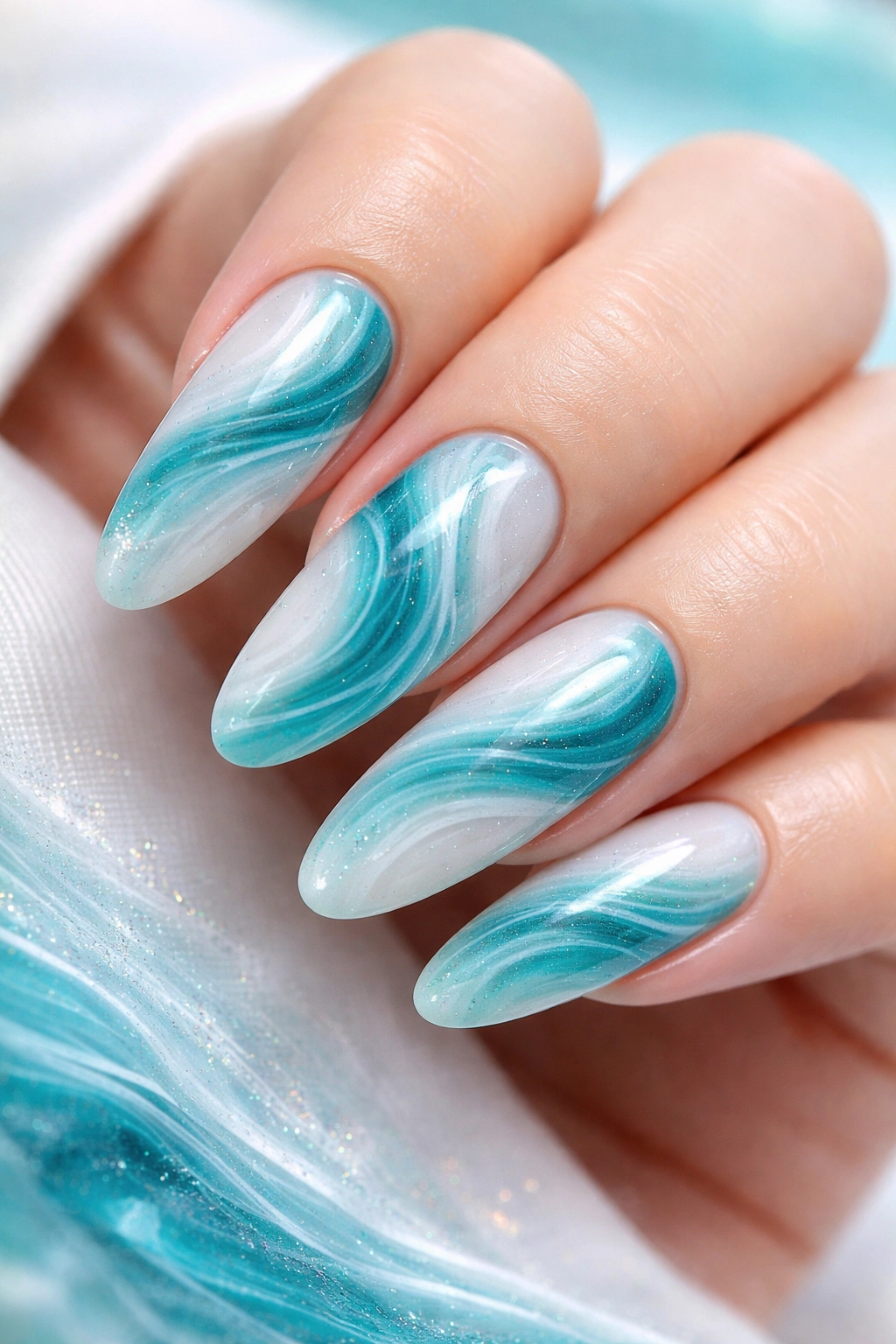 Nails with turquoise and teal ocean-inspired swirls on pale base.