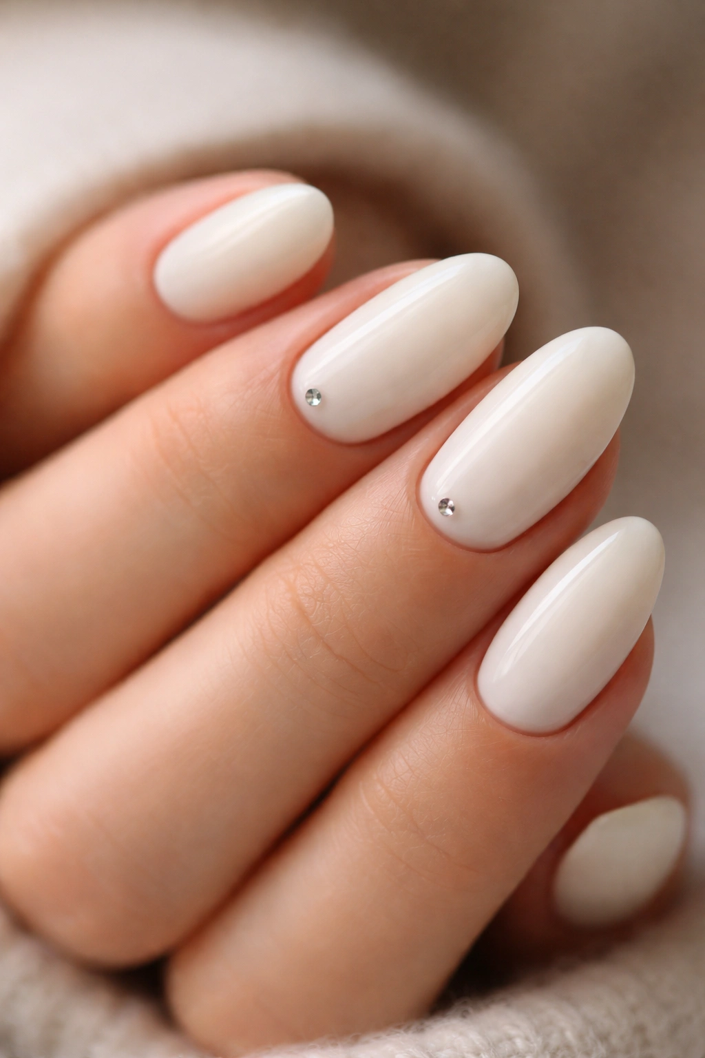 Off-white almond nails featuring tiny rhinestone accents.