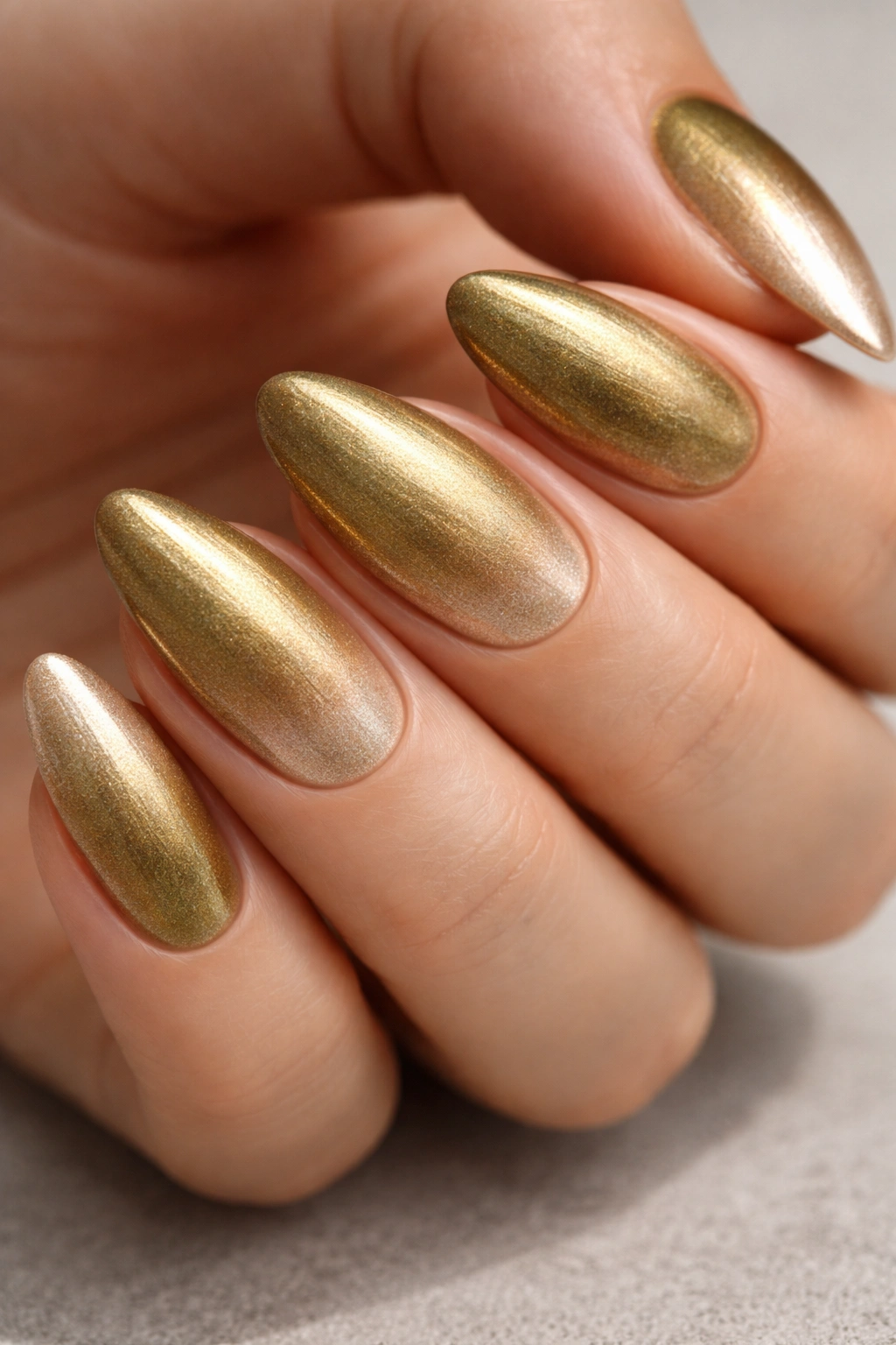 Macro shot of almond nails from olive gold to champagne ombre with metallic sheen