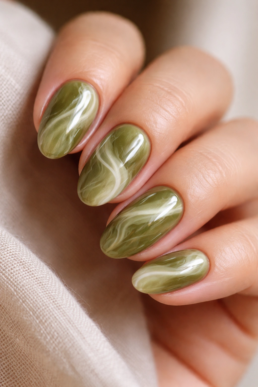 Olive green marble nails with soft white veining on short almond nails