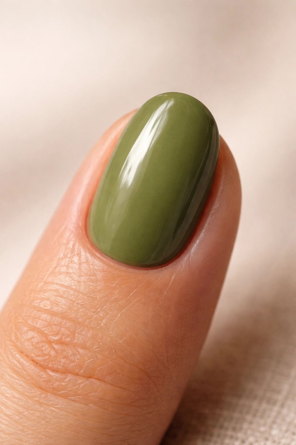 Single olive-green short oval nail against neutral background