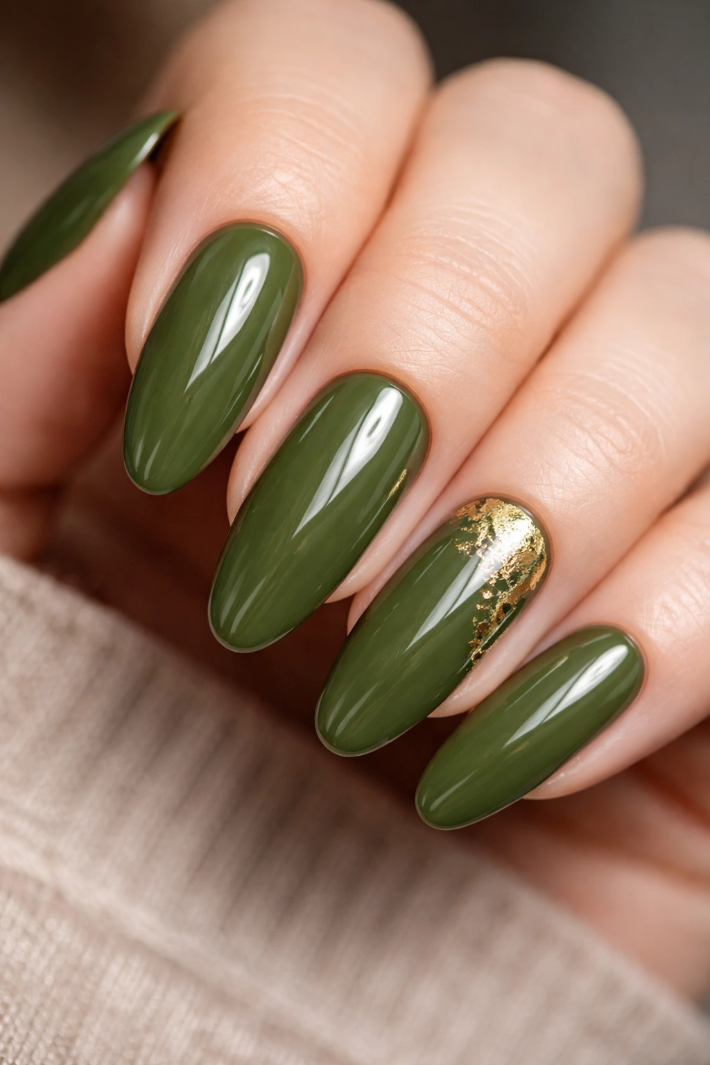 Close-up of long oval nails in olive green with gold foil accents
