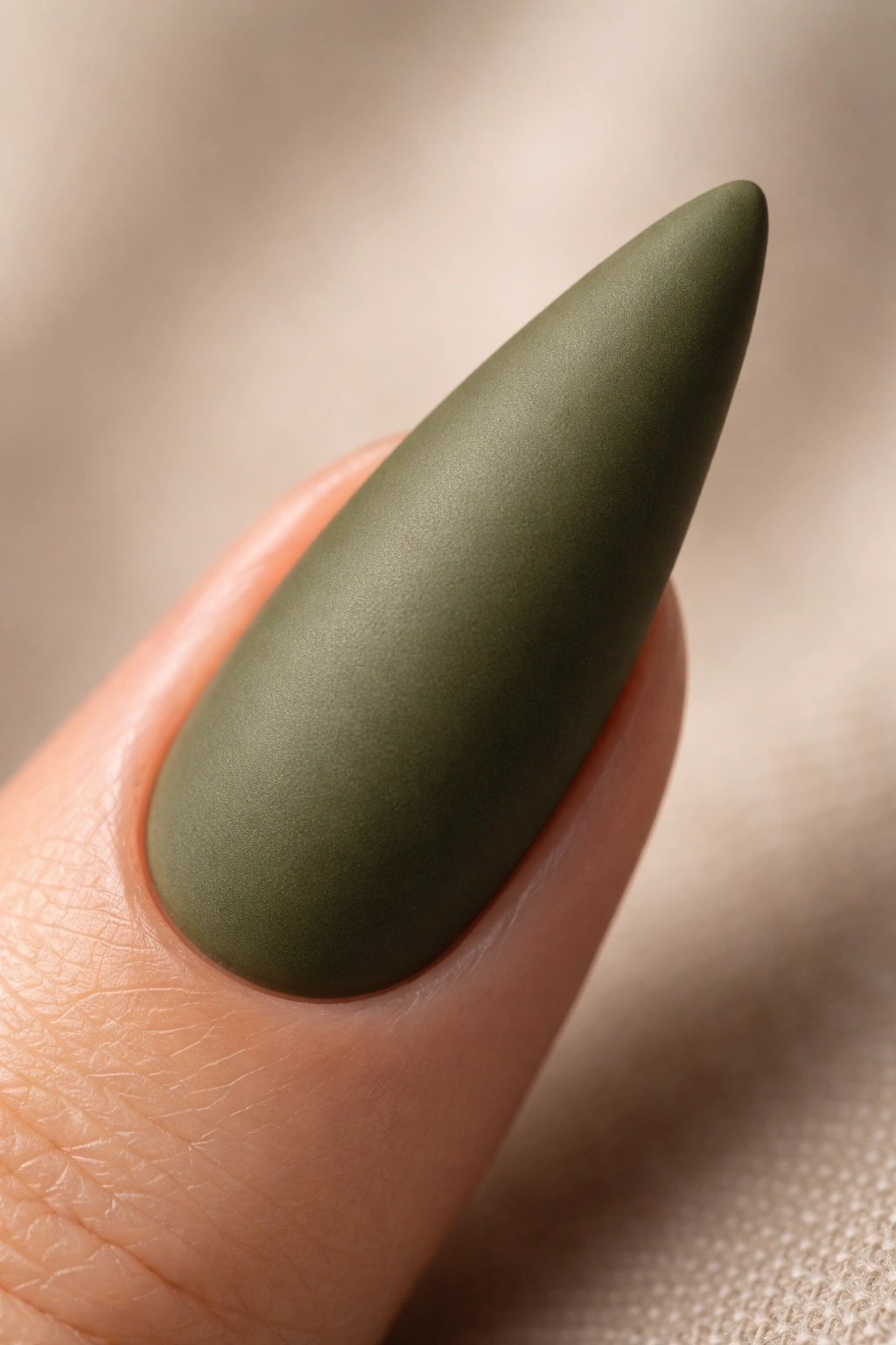Close-up of olive green stiletto nail with matte topcoat.