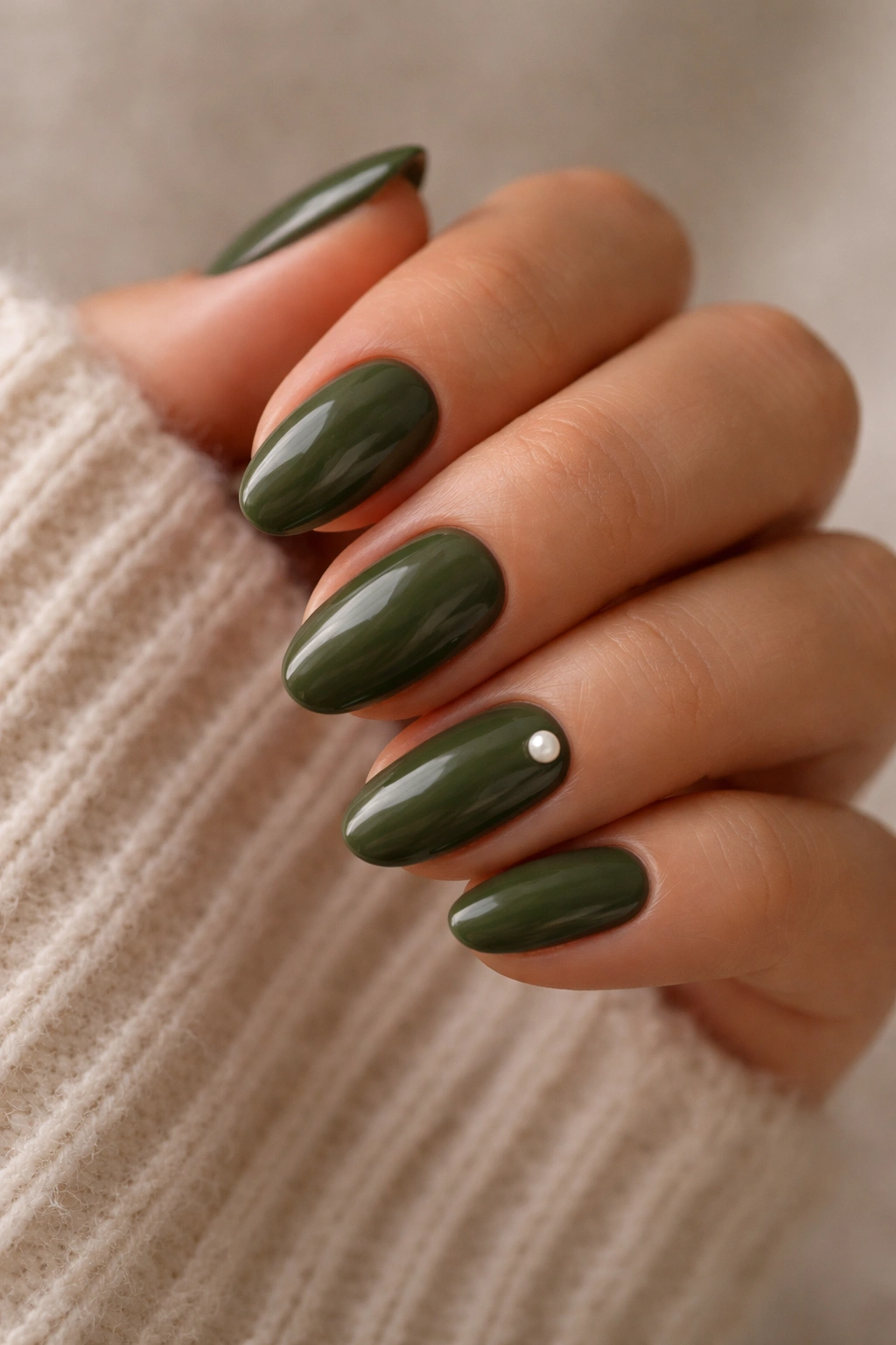 Close-up of olive nails with a tiny pearl accent on a short almond nail