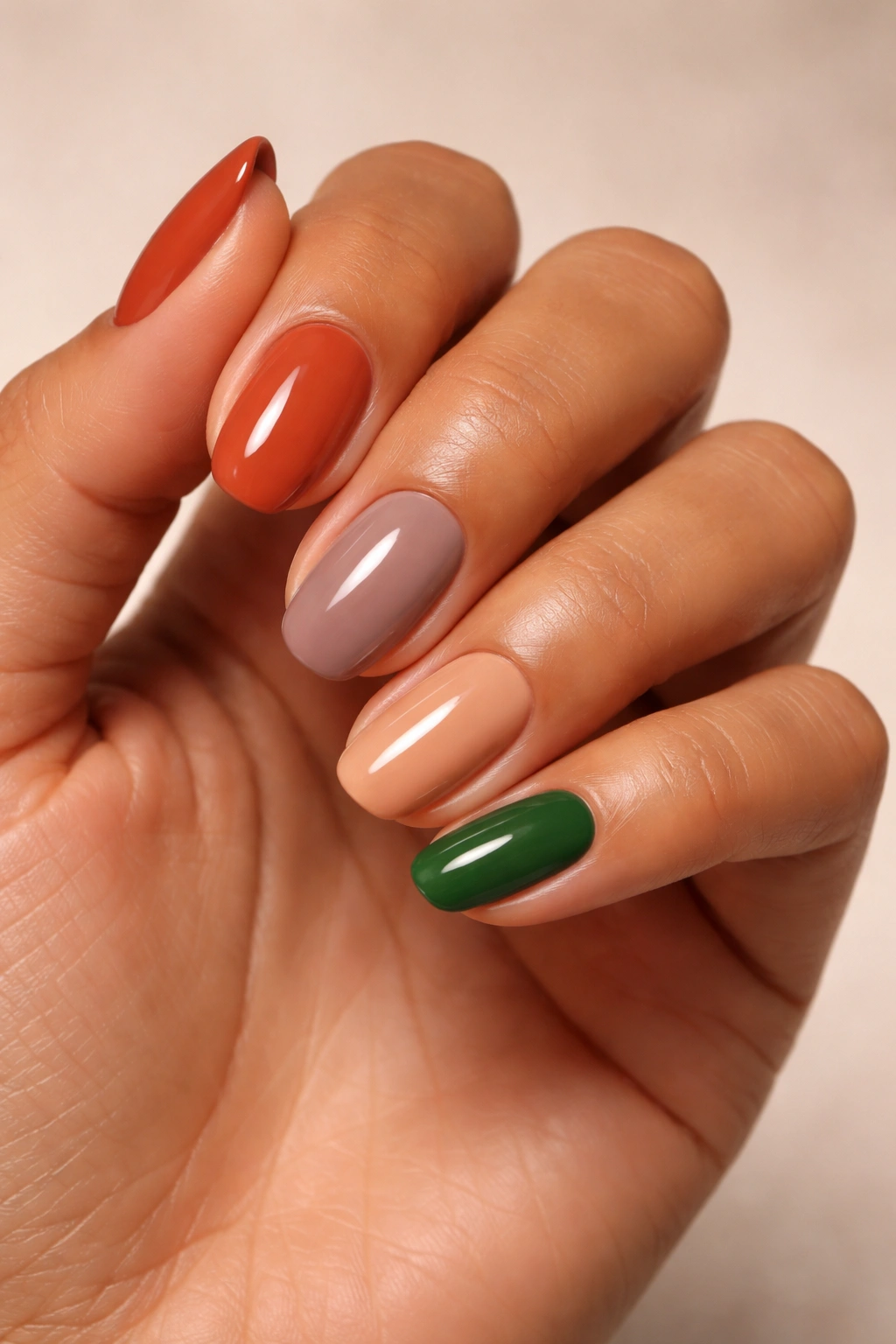 Olive skin hand with terracotta, taupe, warm nude and emerald nails