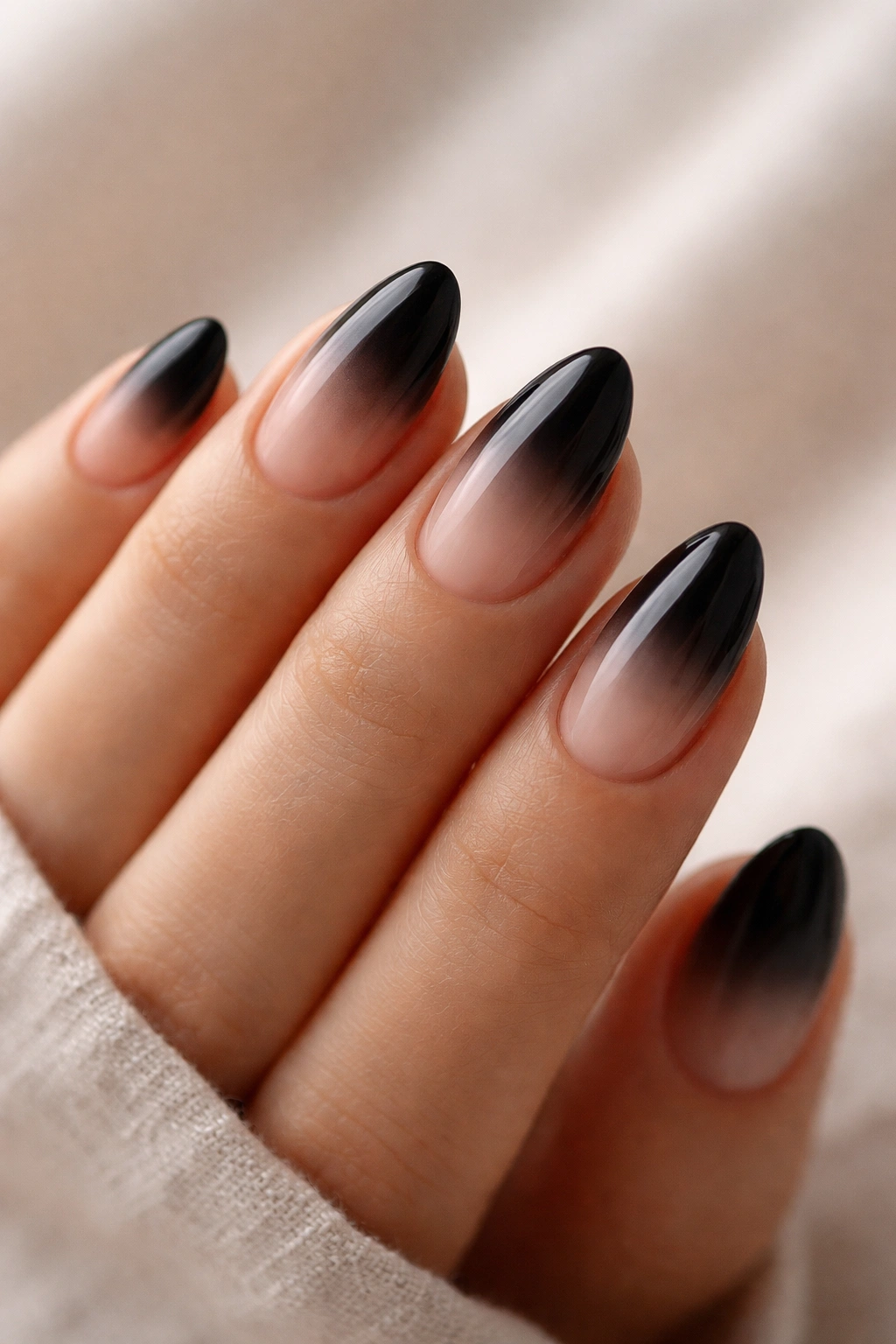 Close-up of black almond nails with a soft ombré fade from clear to black.