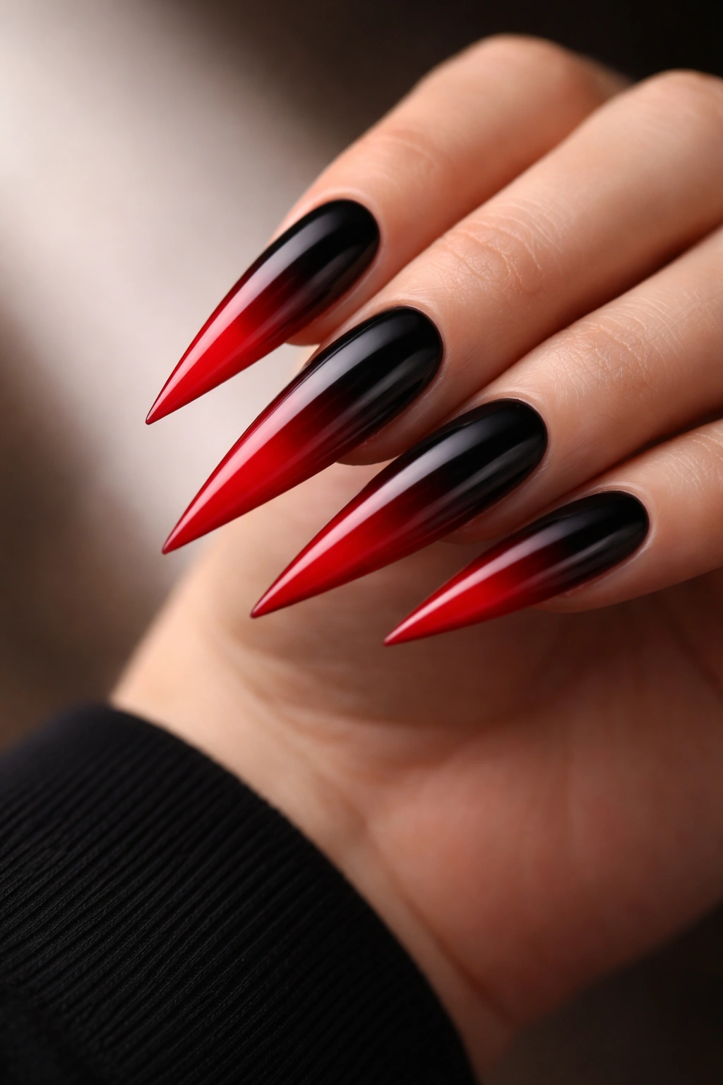 Close-up of black to red ombre on elongated stiletto nails