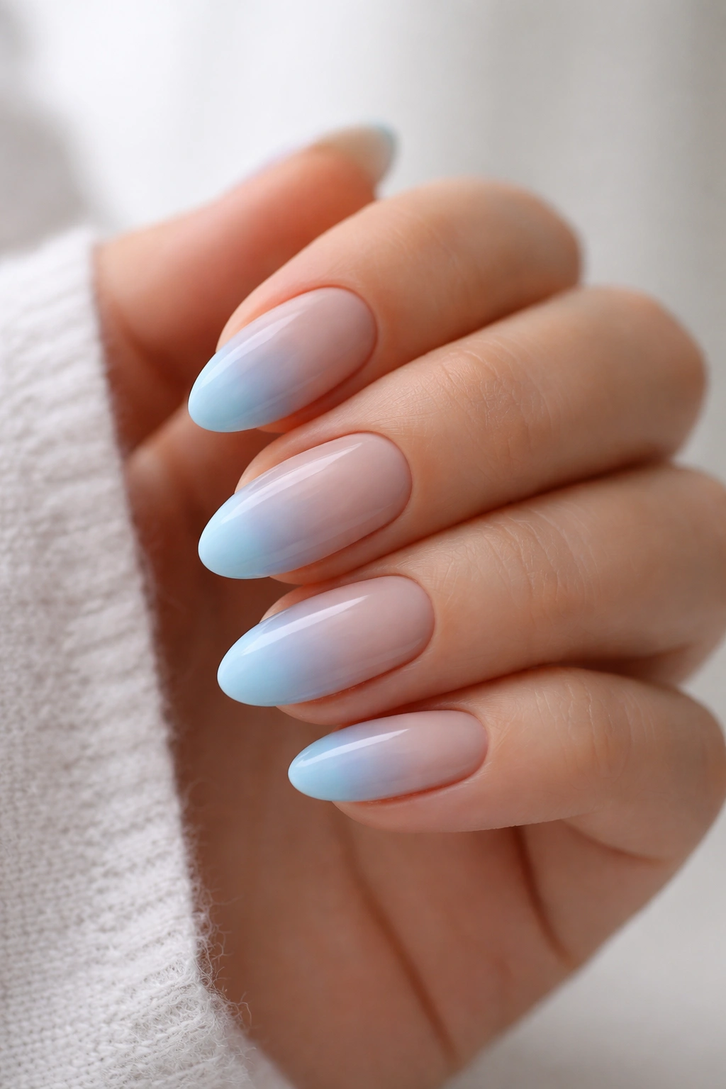 Close-up of short almond nails with a soft blue gradient fade.