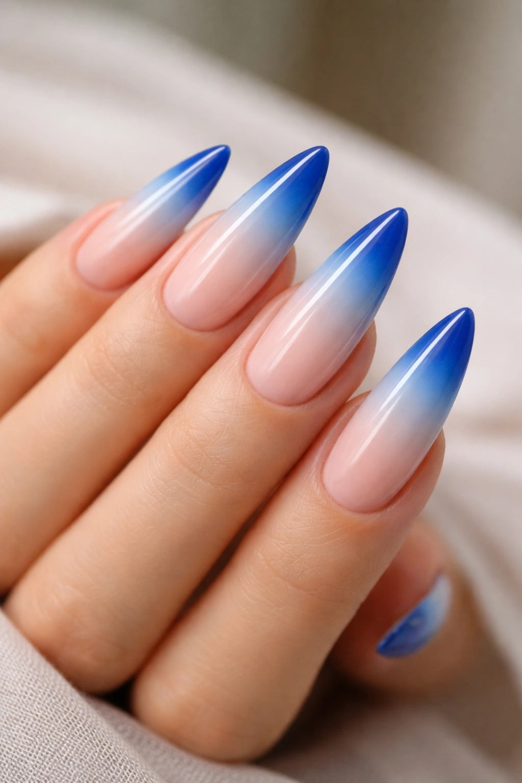 Close-up of ombre blue French tip nails on stiletto nails with smooth gradient