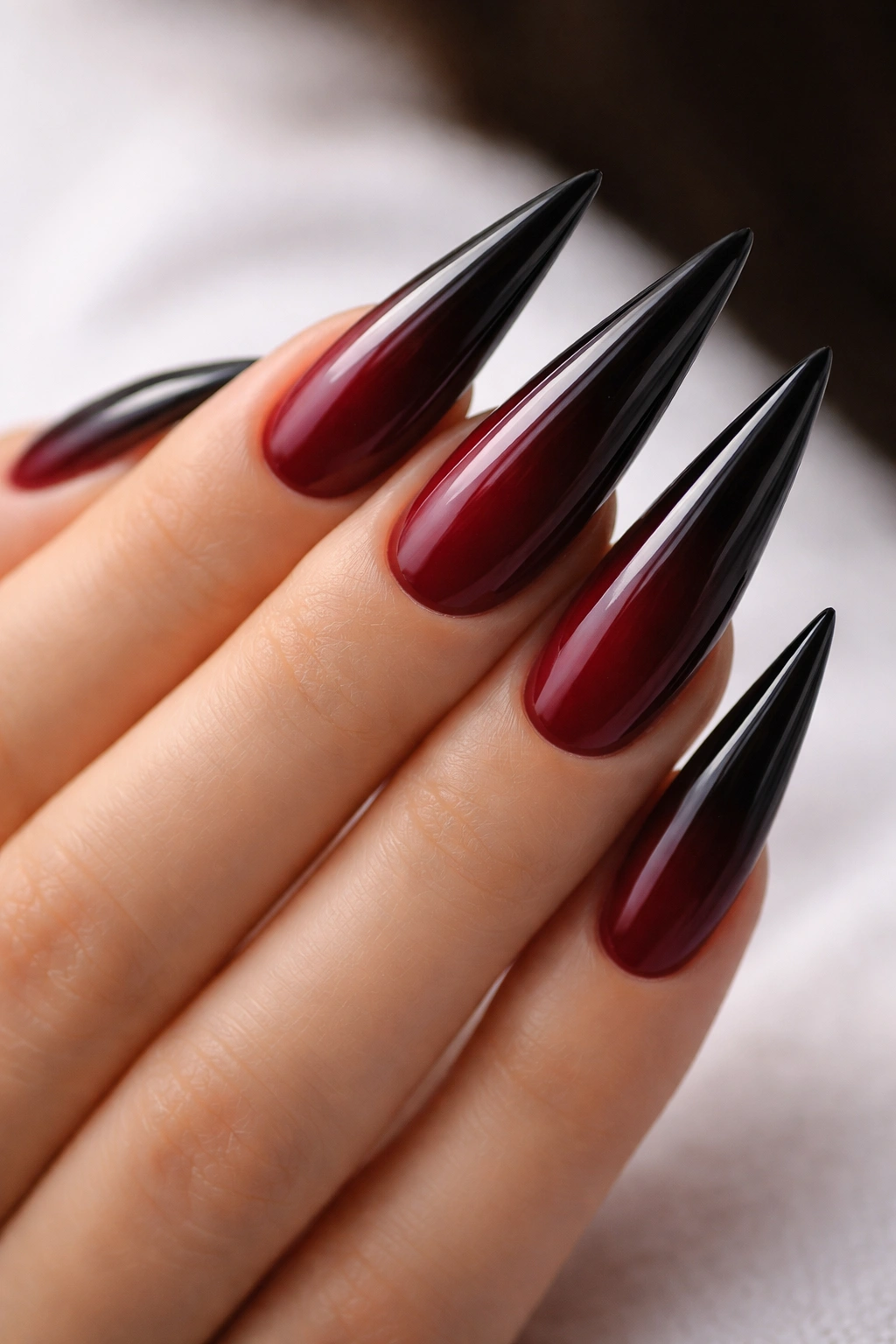 Close-up of burgundy to black ombré stiletto nails with a seamless gradient.