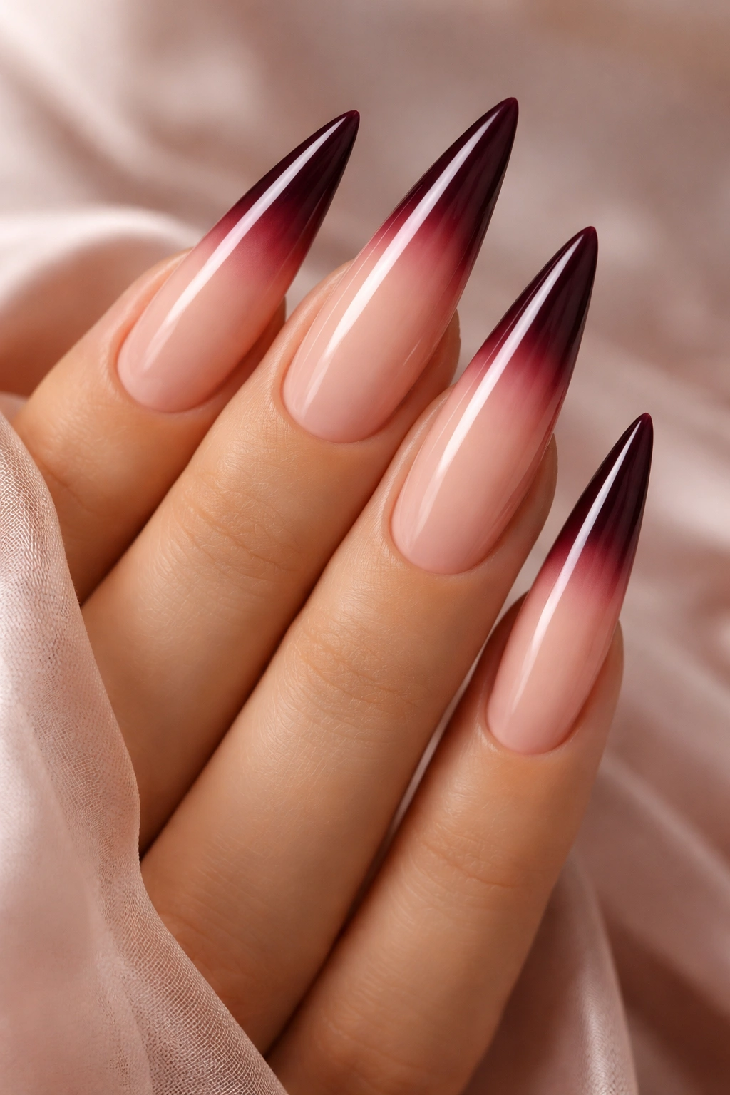 Close-up of ombre burgundy to pink French tips on nude stiletto nails