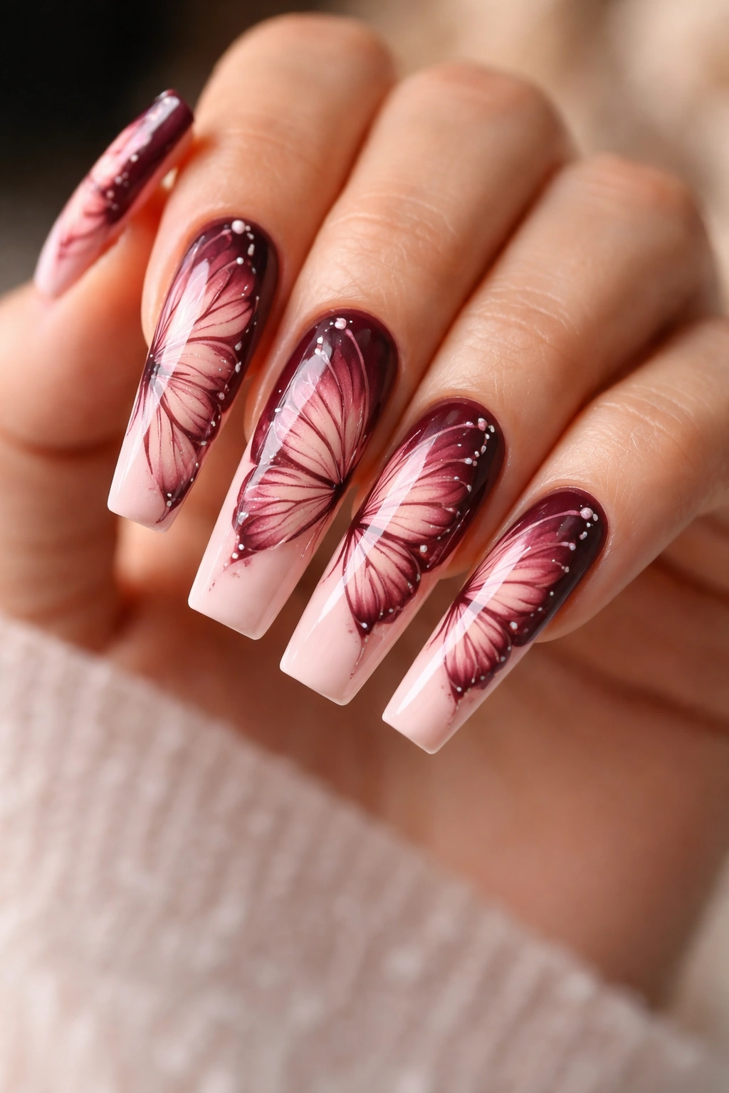 Coffin nails with burgundy-to-blush ombre butterfly wings on a solid base.