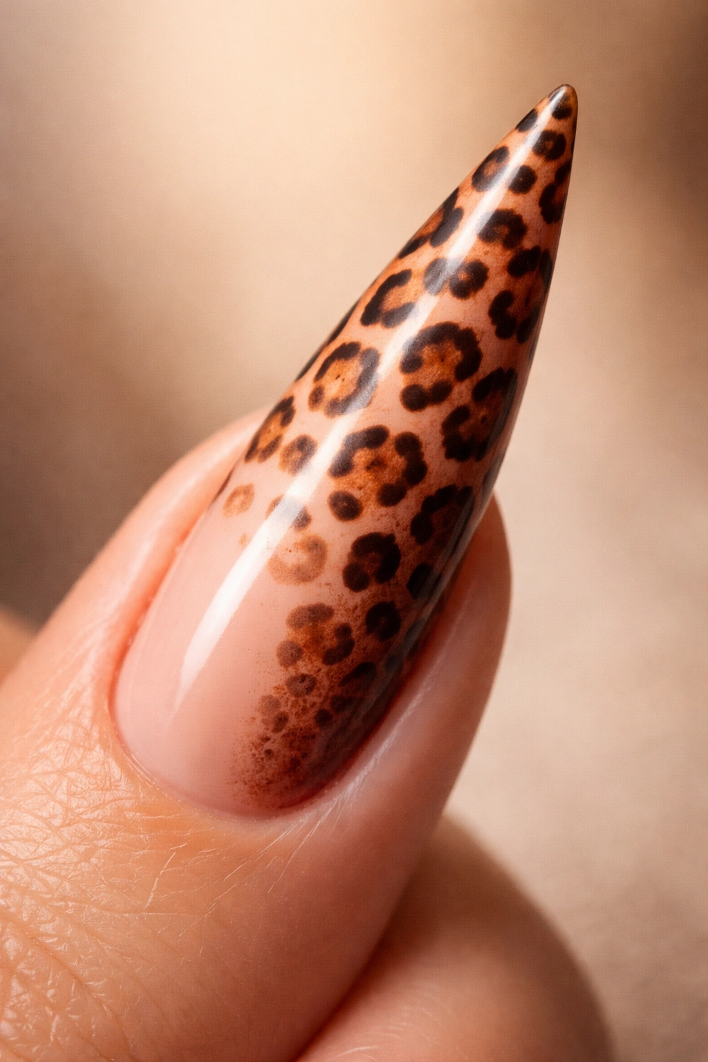 Close-up of ombre cheetah stiletto nail with pink-to-burnt-sienna gradient and color-shifting spots