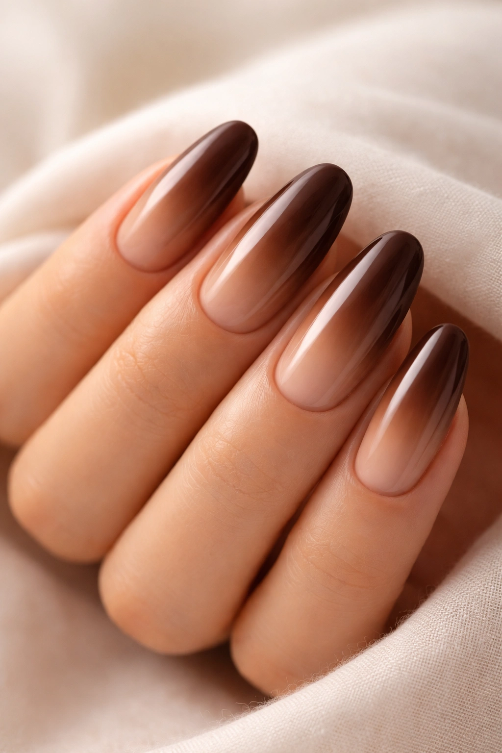Close-up of long rounded nails with chocolate brown to nude gradient
