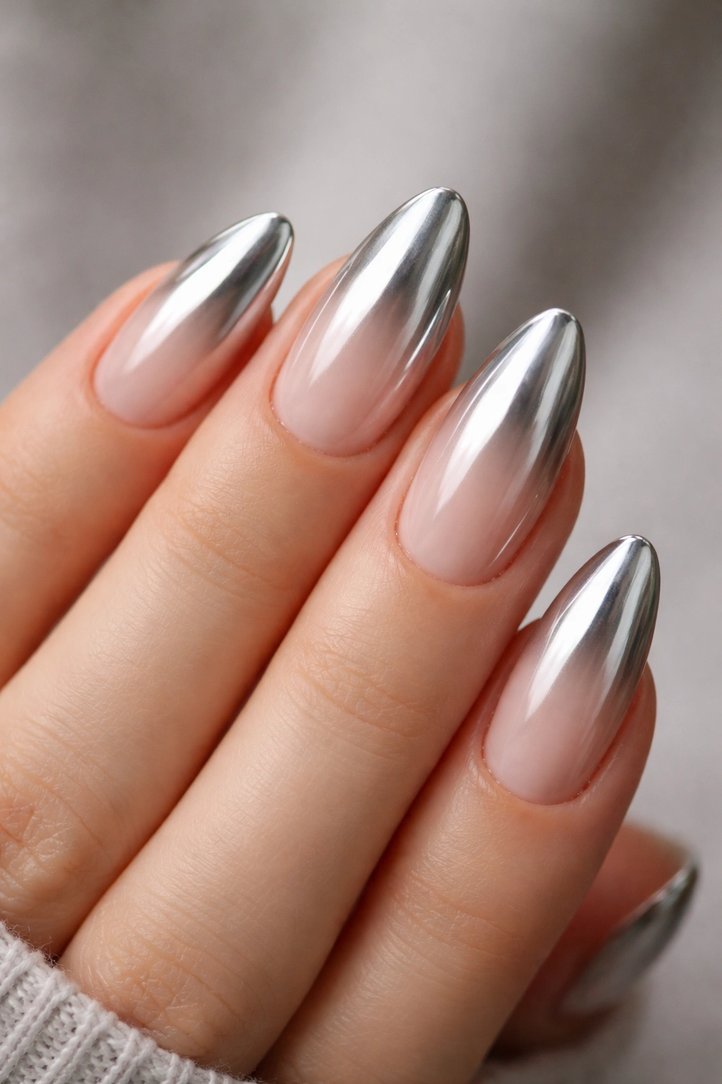 Close-up of almond-shaped nails with chrome ombré gradient from sheer to reflective.