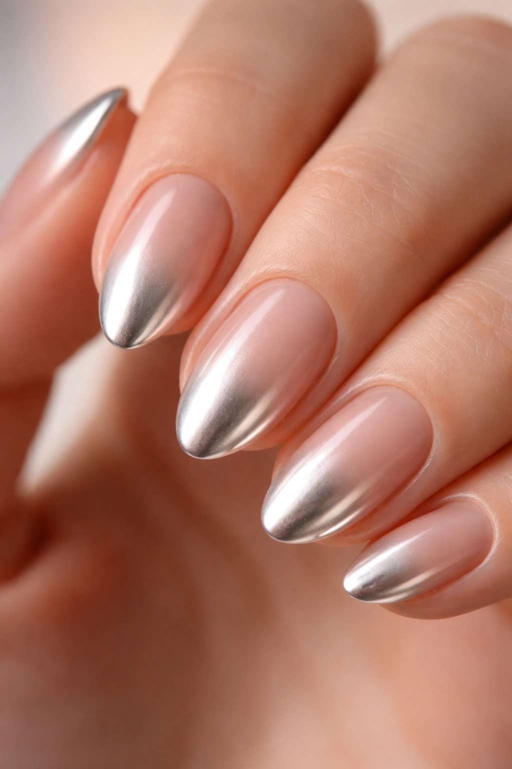 Close-up of a short almond nail with nude-to-chrome ombré gradient