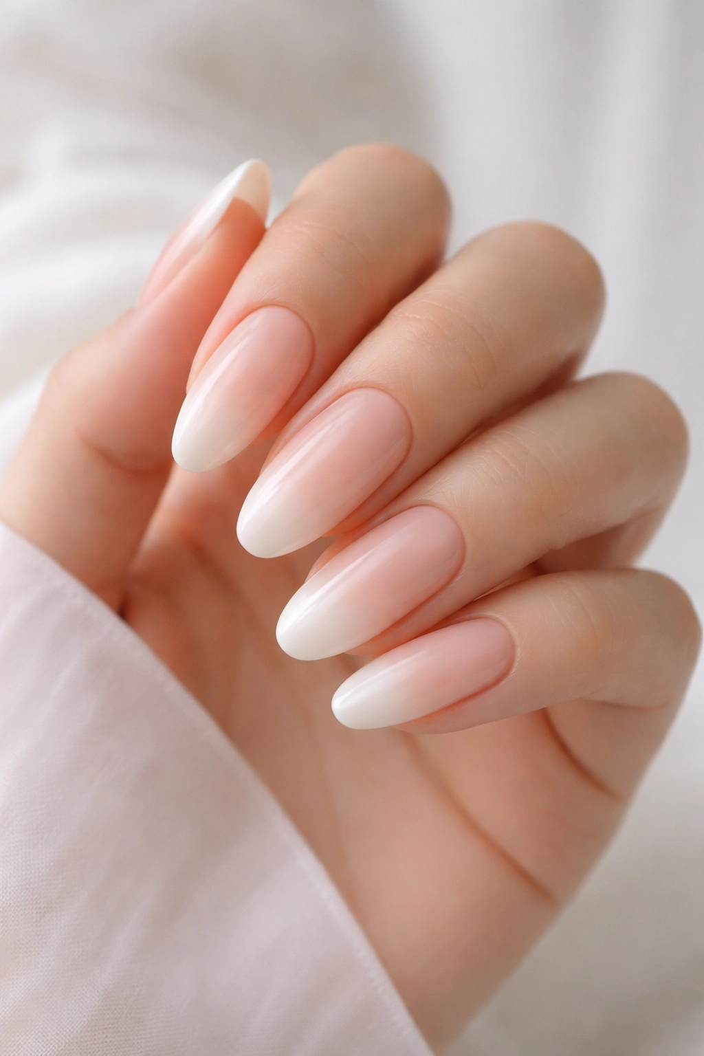 Long round nails with nude to ivory ombre on a hand