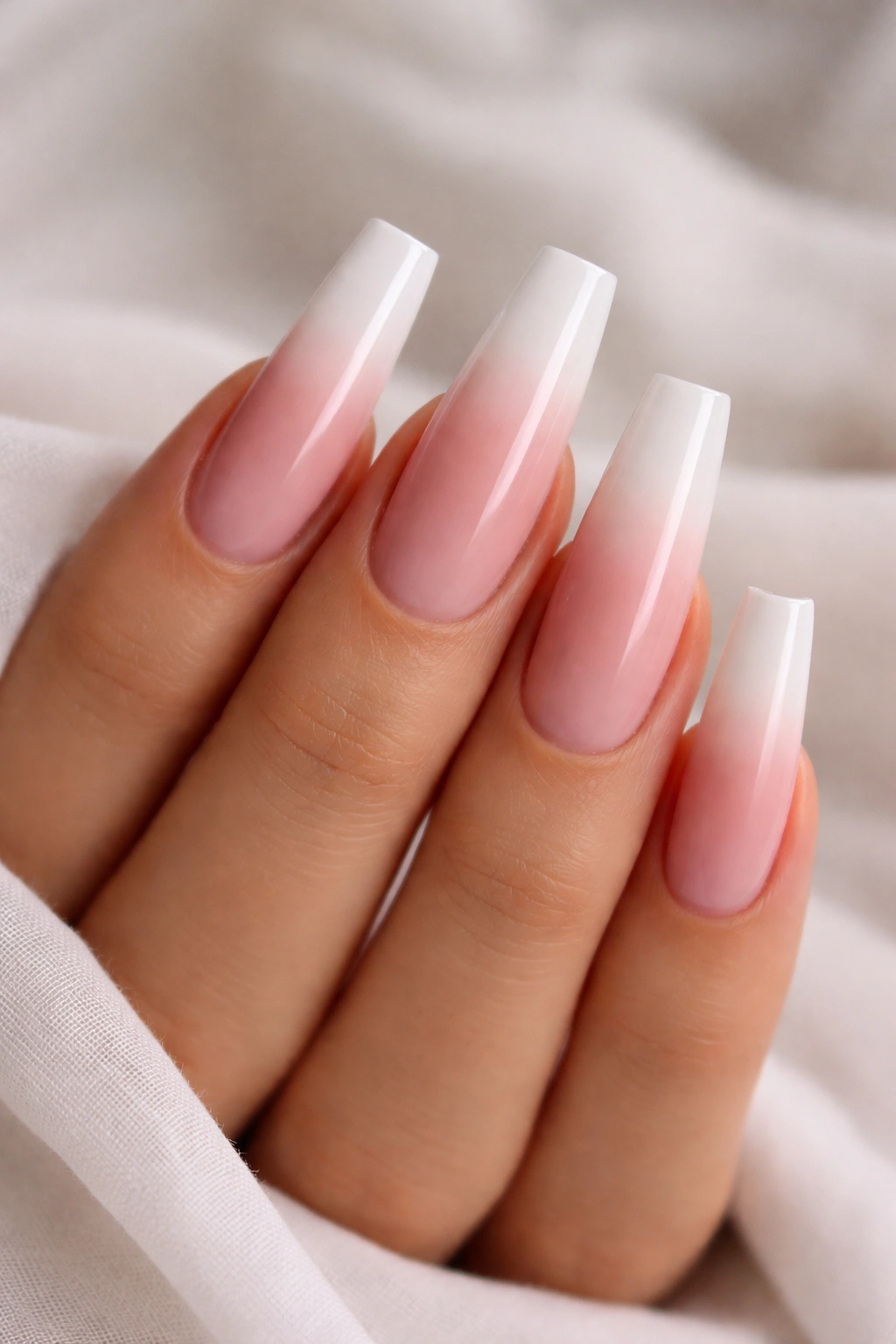 Close-up of long coffin nails with pink to white gradient tips