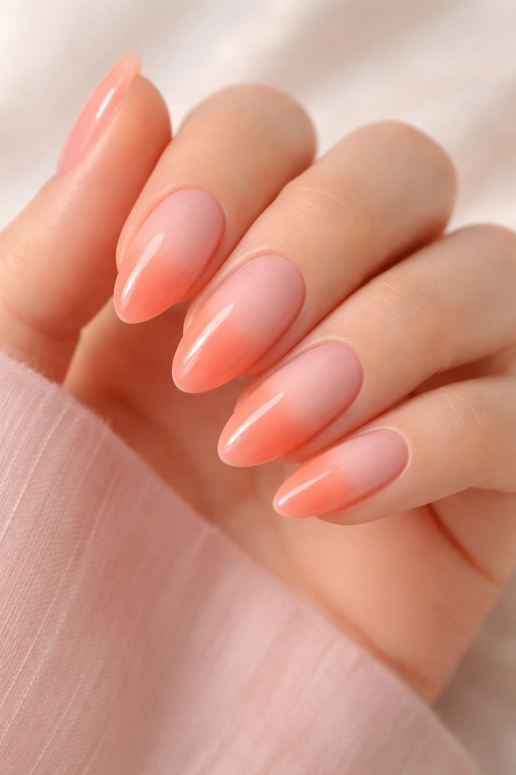 Close-up of gradient nails from pale pink to coral